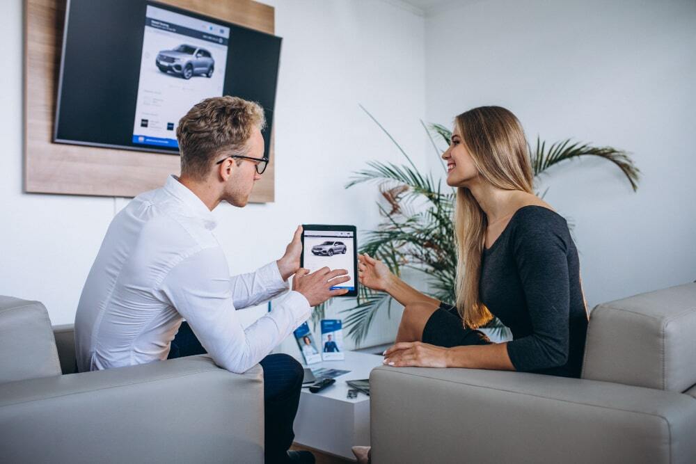 Car Marketing: Turn Your Vehicle into a 24/7 Advertising Machine 1 Car Marketing Turn Your Vehicle into a 247 Advertising Machine (A dealer is dealing with client while helping them explore more options and how they can use their car)
