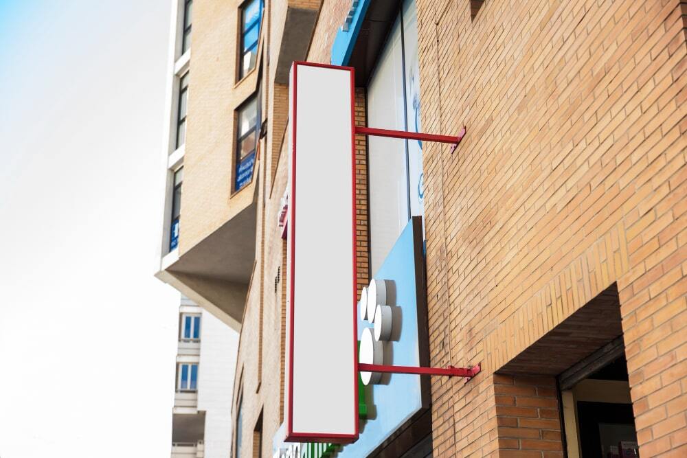 Tips for Effective Outdoor Signage Boards 4 Image showing a signage board placed above the shop in vertical way for catching eyes of the pedestrians (Strategic Placement for Maximum Impact)