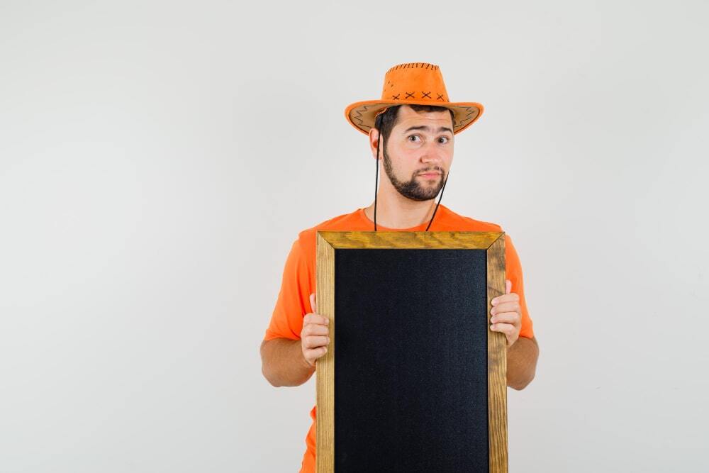 Tips for Effective Outdoor Signage Boards 4 Tips for Effective Outdoor Signage Boards (A person standing confused holding an empty signage board)