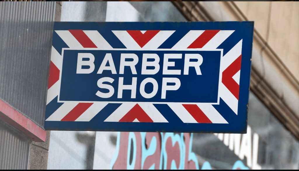 What Exactly is an Aluminium Tray Sign? 1 A classic barber shop sign featuring red, white, and blue stripes, indicating a place for haircuts and grooming services.