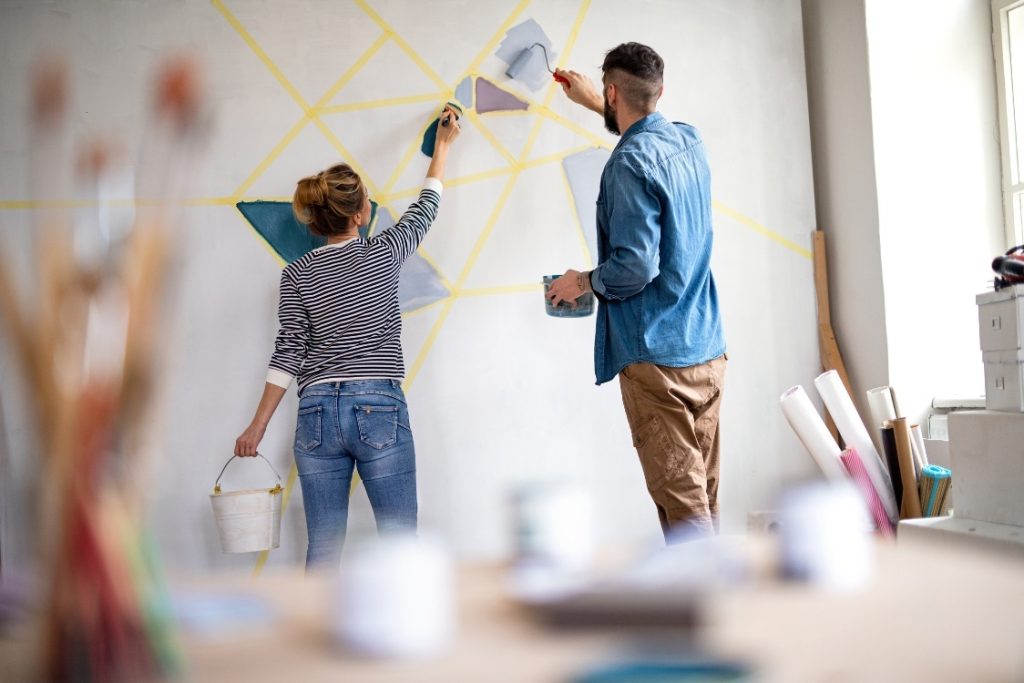 Why Smart Businesses Are Using Custom Wall Graphics to Wow Visitors 2 A man and woman collaboratively painting a colorful mural on a wall, showcasing their creativity and teamwork