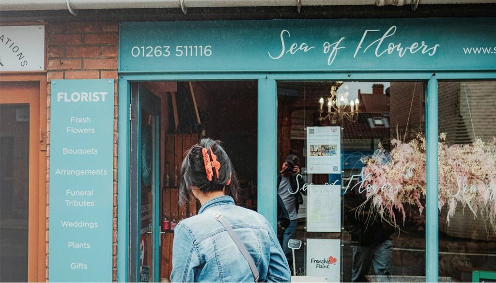Interactive Outdoor Displays: A Solution for Any Environment 1 This image is showing a customer being attracted to a shop from its outdoor sign, referring to the Benefits of Using Interactive Outdoor Signs