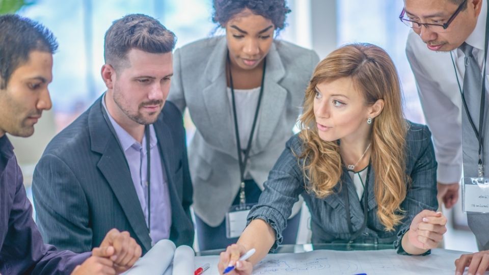 In the image a business strategy consultant can be seen guiding a team of professionals.