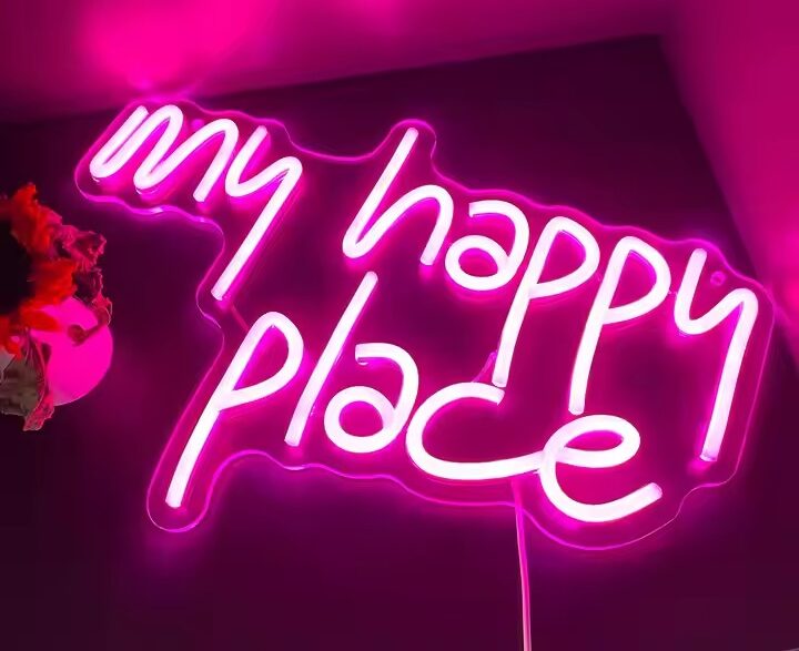 Neon signs displaying pink illuminated “my happy place” text mounted on an indoor wall