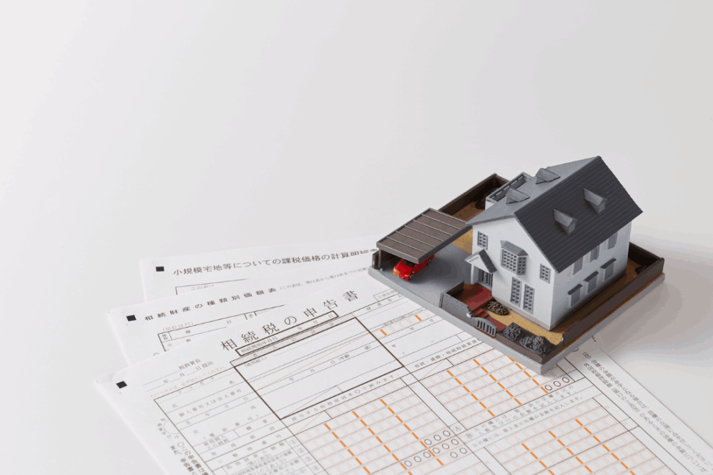 Documents and a miniature house symbolizing tax obligations for landlords, representing the UK Non-Resident Landlord Scheme.