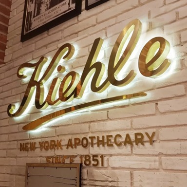 Reception sign displaying illuminated script logo letters mounted on white brick wall