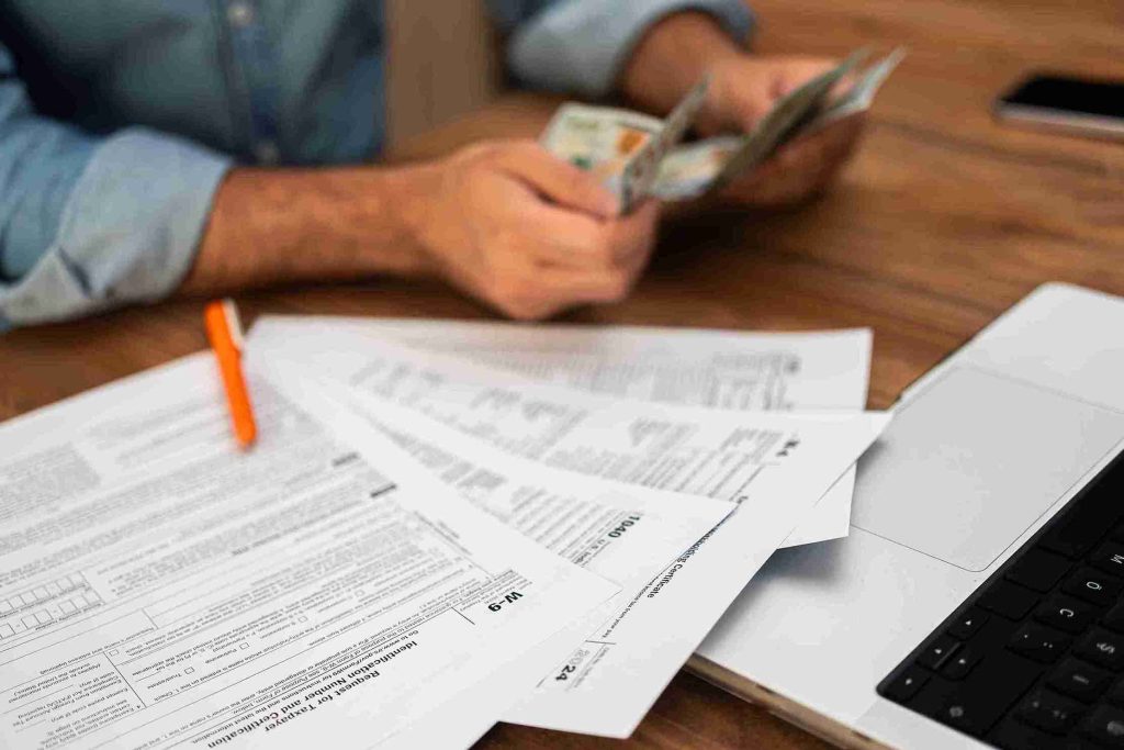 Picture shows a Tax return sheet that need to be filled, while having tax return written on wooden dices as well.