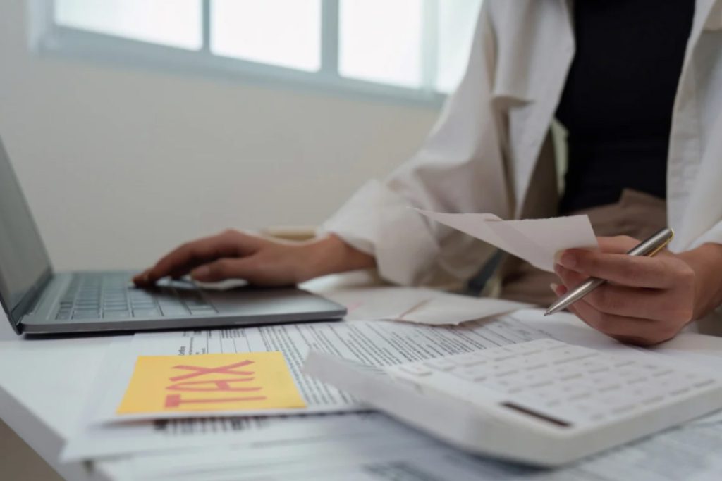 (A person calculating finances with a sticky note labeled TAX, illustrating the importance of legal tax advice to avoid tax evasion.) is tax evasion illegal