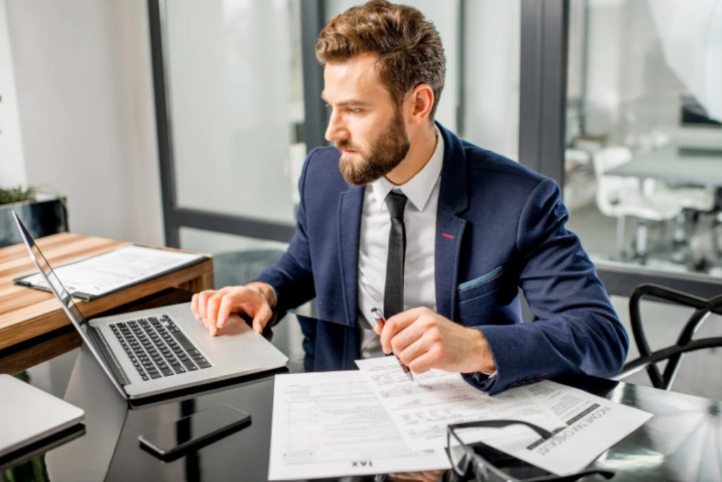 (A professional reviewing financial documents on a laptop, highlighting the difference between tax avoidance vs tax evasion in the UK.)