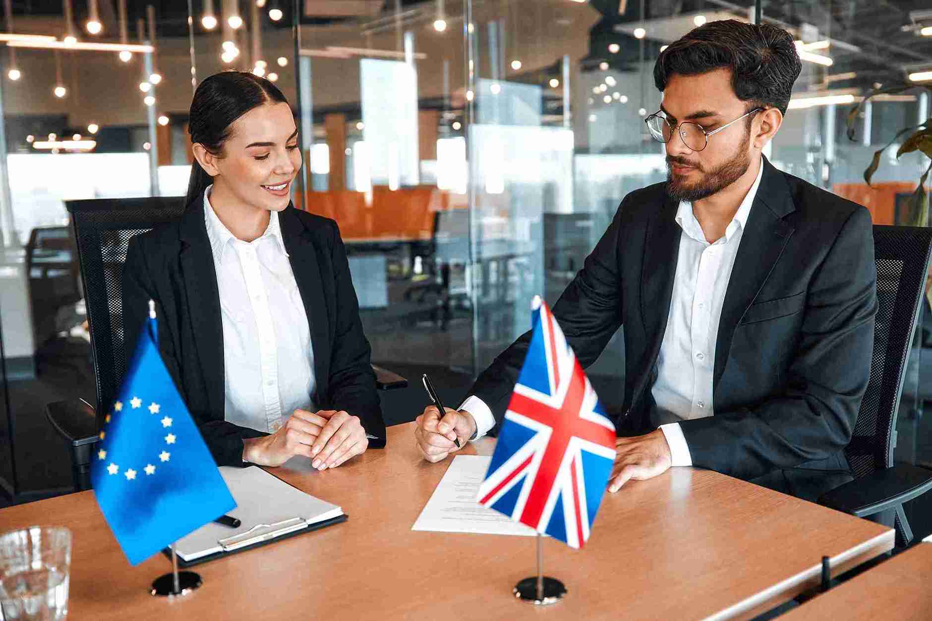 Two business professionals seated at a table, focused on signing important documents together.