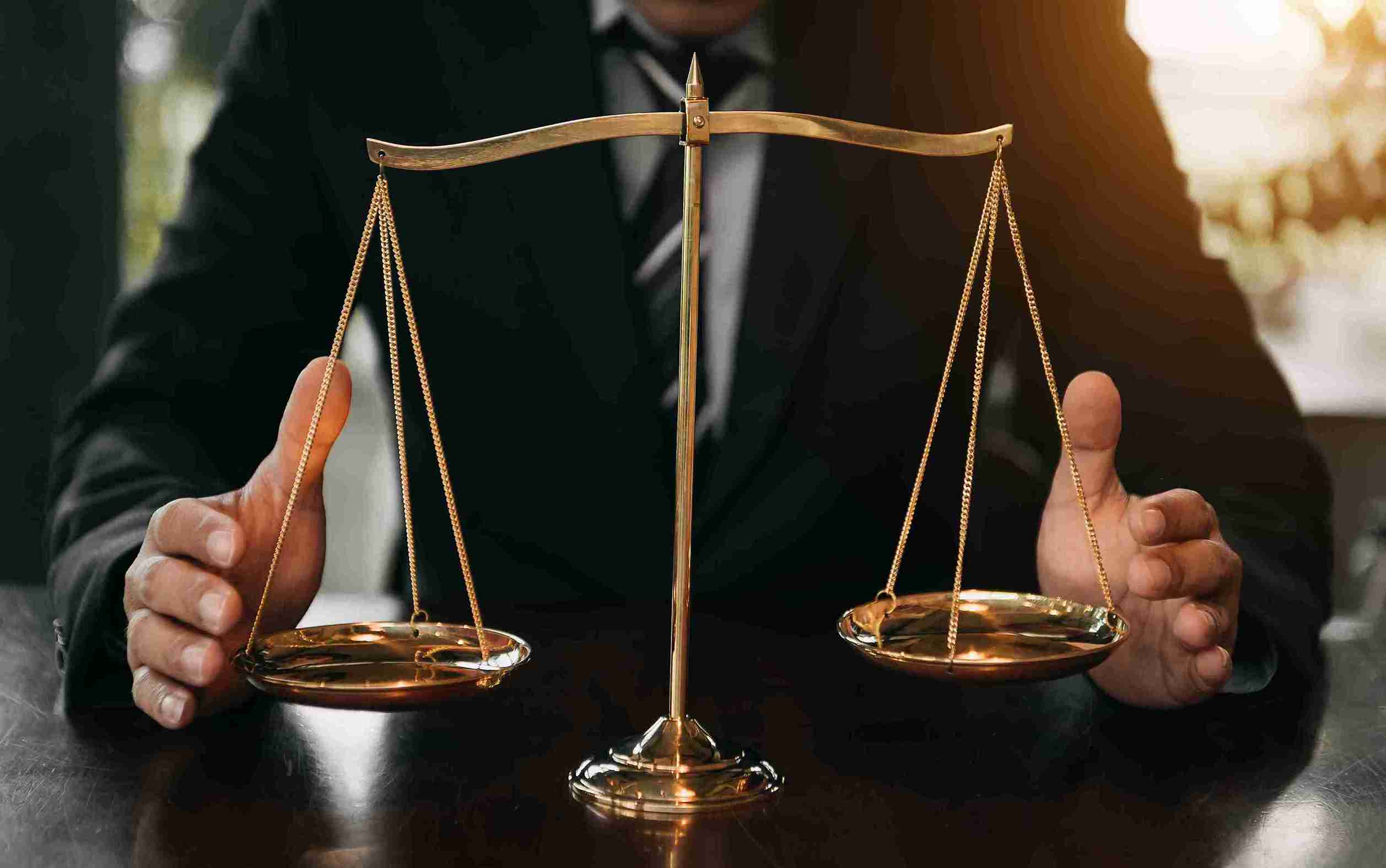 A man in a suit holds two scales, symbolizing justice and balance in a professional setting.