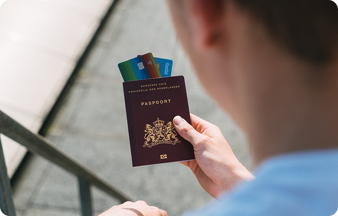 A man holds a passport and several credit cards, preparing for travel or financial transactions.