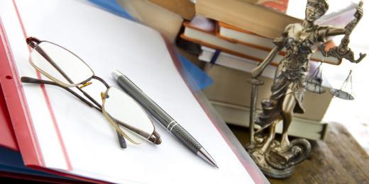 Lawyer's desk featuring glasses, a pen, and legal books, symbolizing judicial review in the UK.