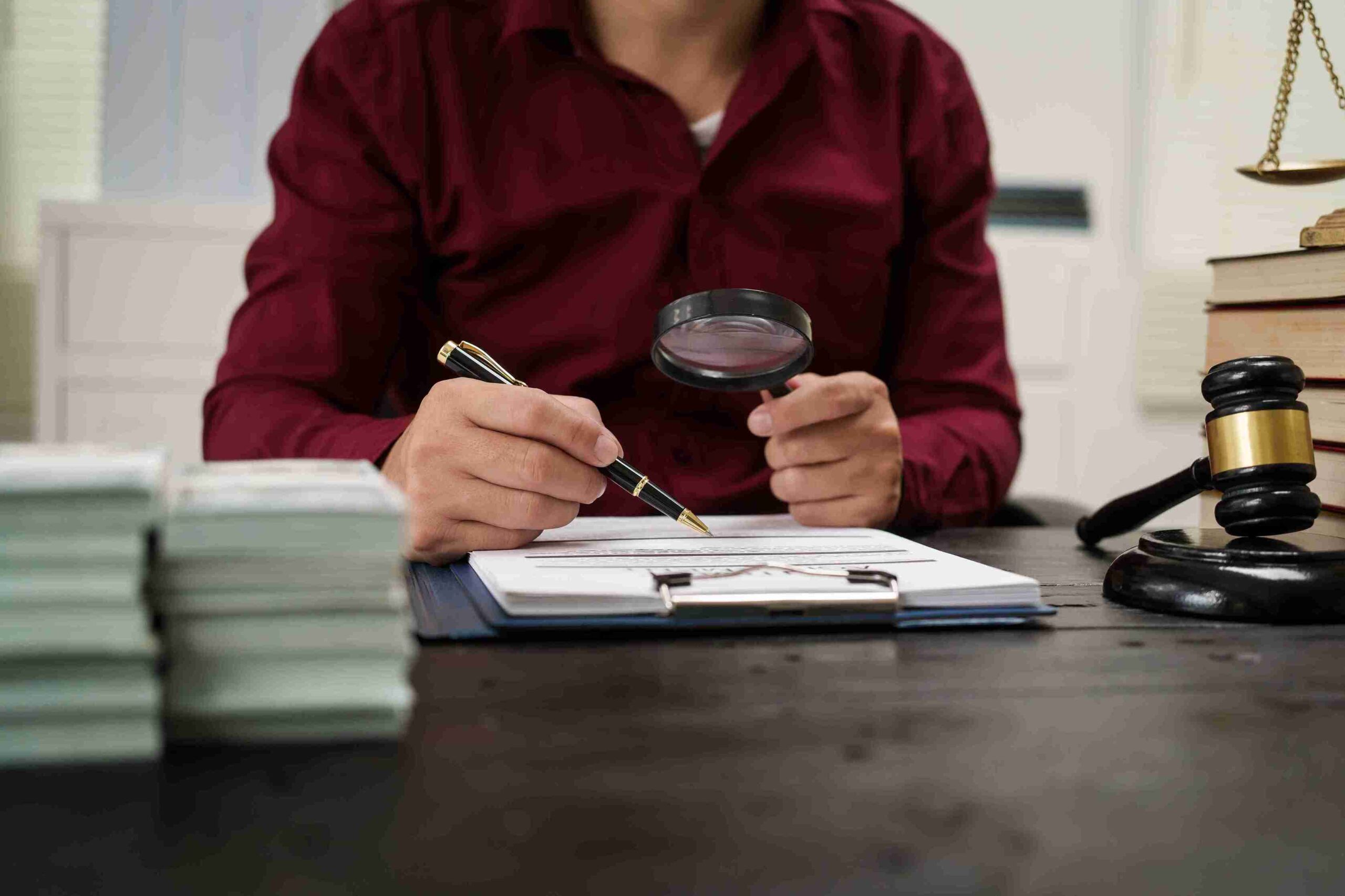 A lawyer focused on writing notes on a legal pad, surrounded by legal documents and a pen.