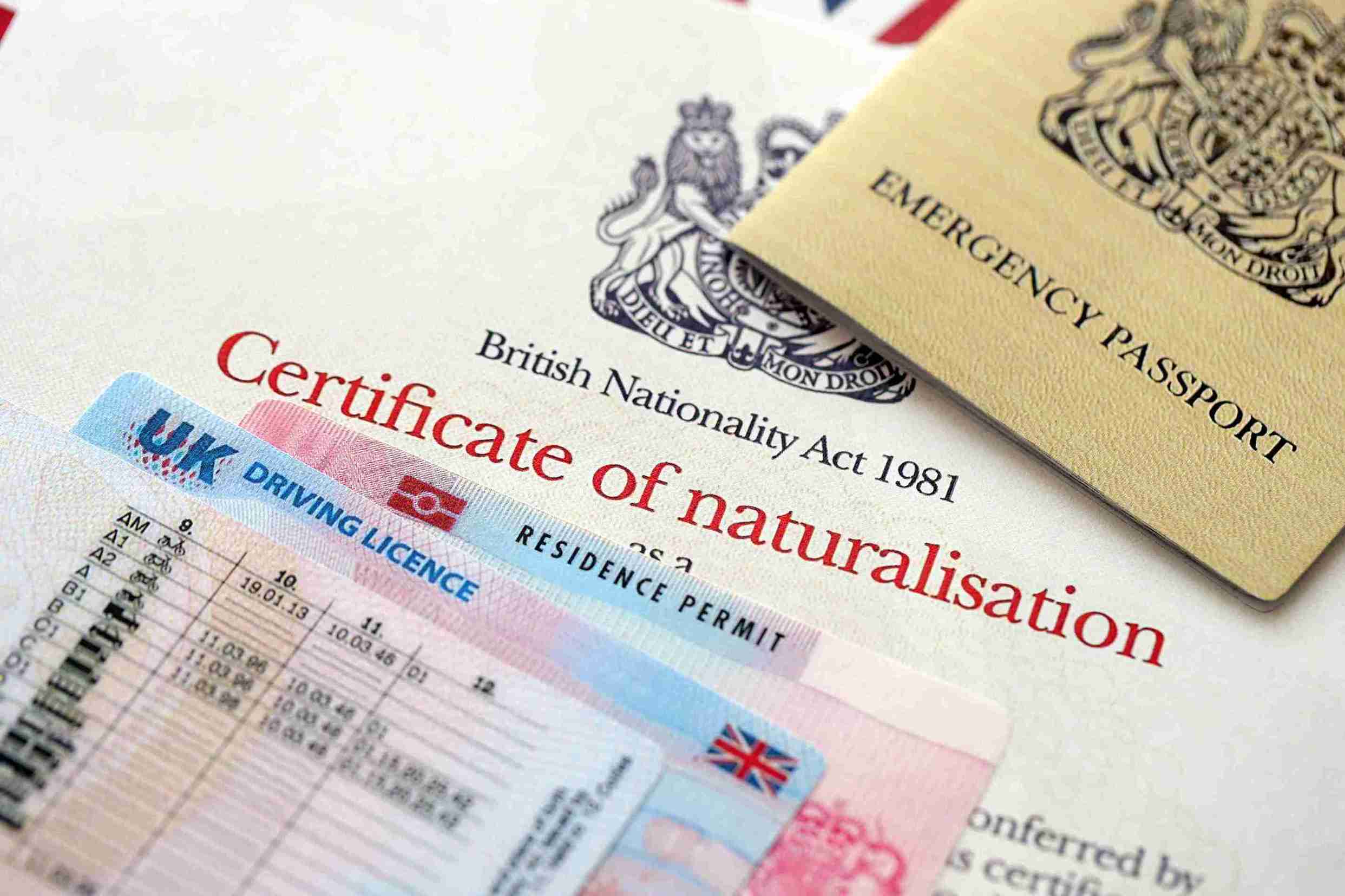 UK certificate of naturalisation form displayed on a desk, with a pen and a passport nearby.