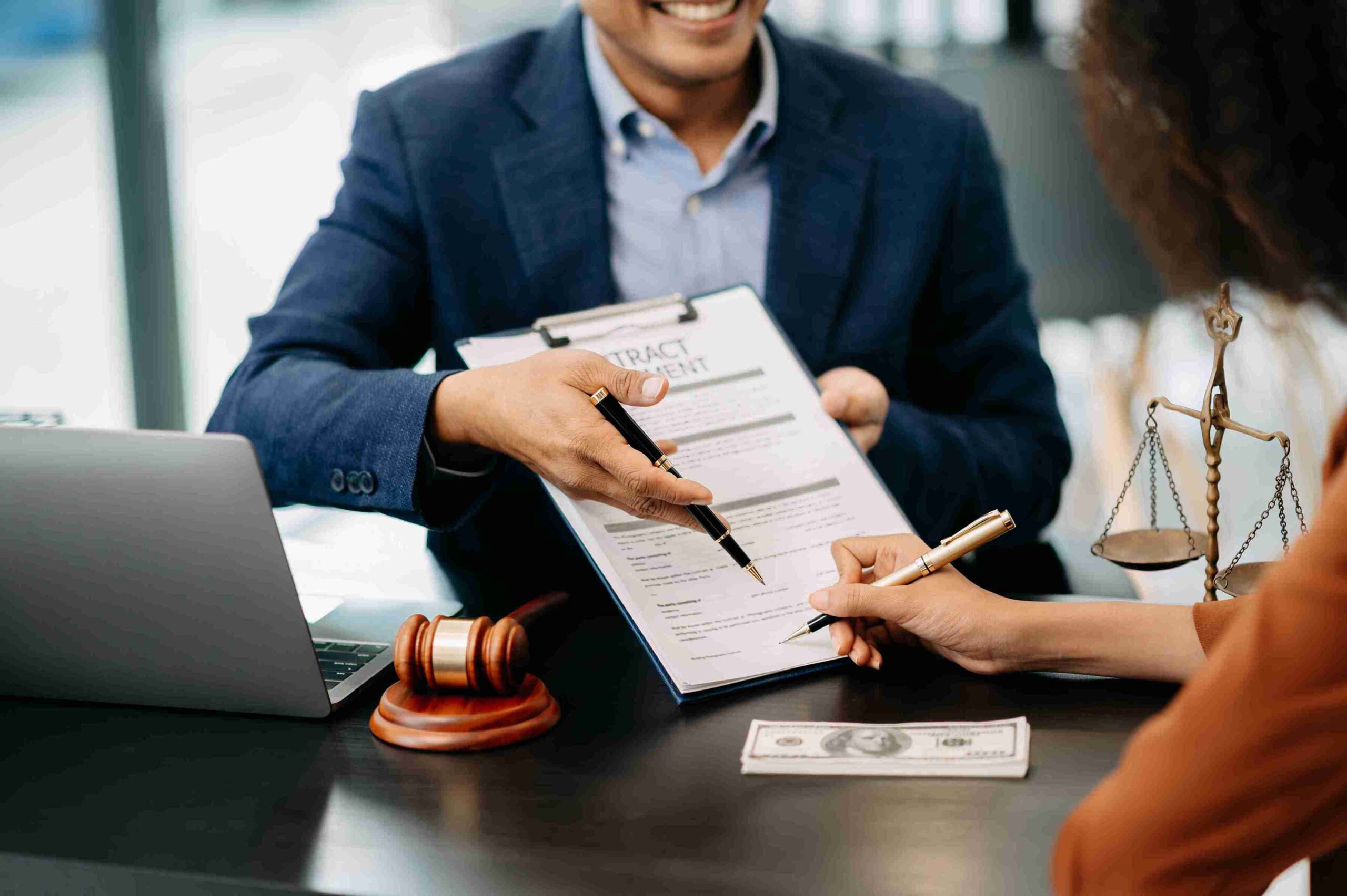 A lawyer and client are seated at a table, signing a contract together, symbolizing a legal agreement.