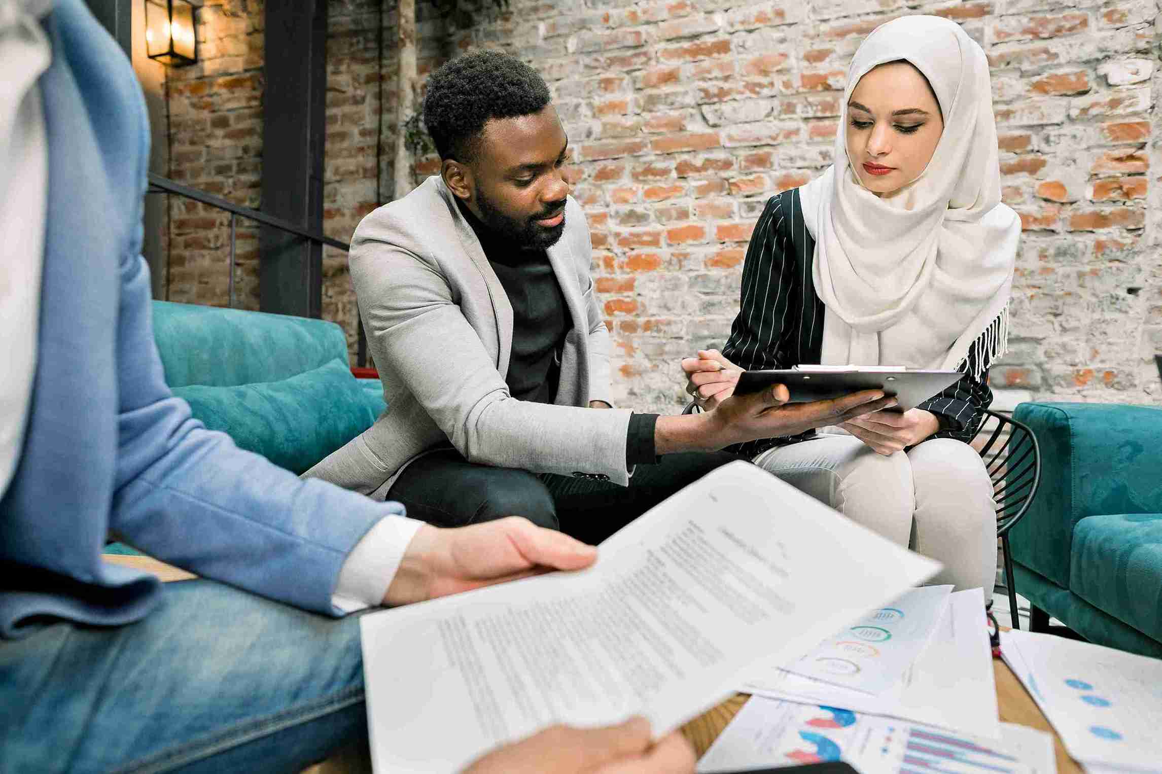 Man and woman reviewing tablet and documents in modern office, representing UK and Shariah compliance for ethical legal solutions.