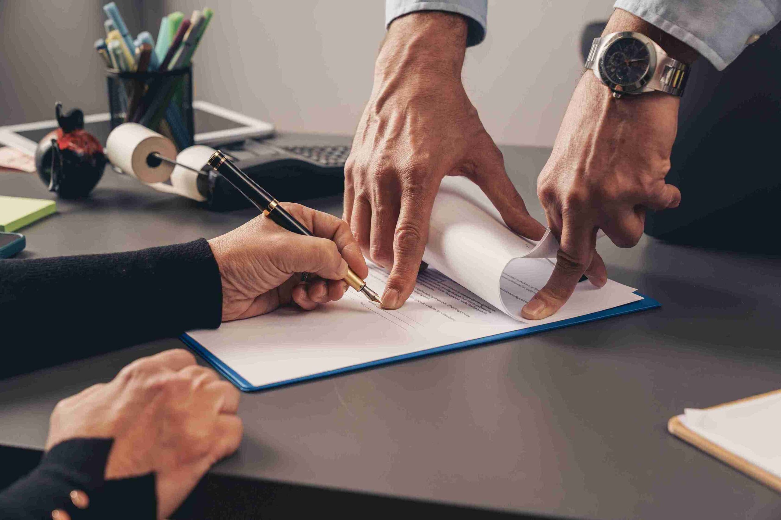 Two people signing a document at a desk, representing clear expert legal advice for drafting a will.