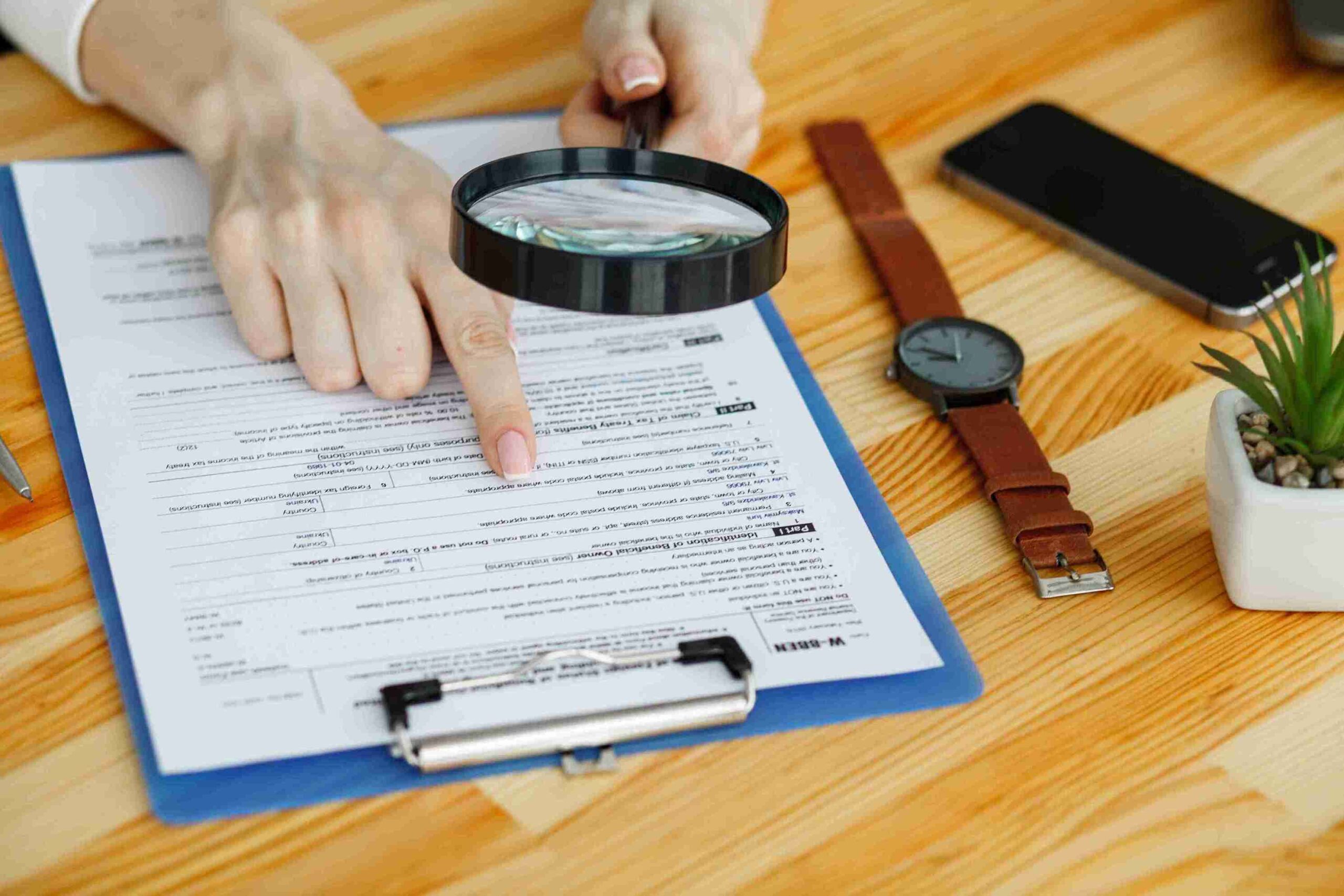 Person examining document with magnifying glass, representing professional insights to address VAT audit risks.