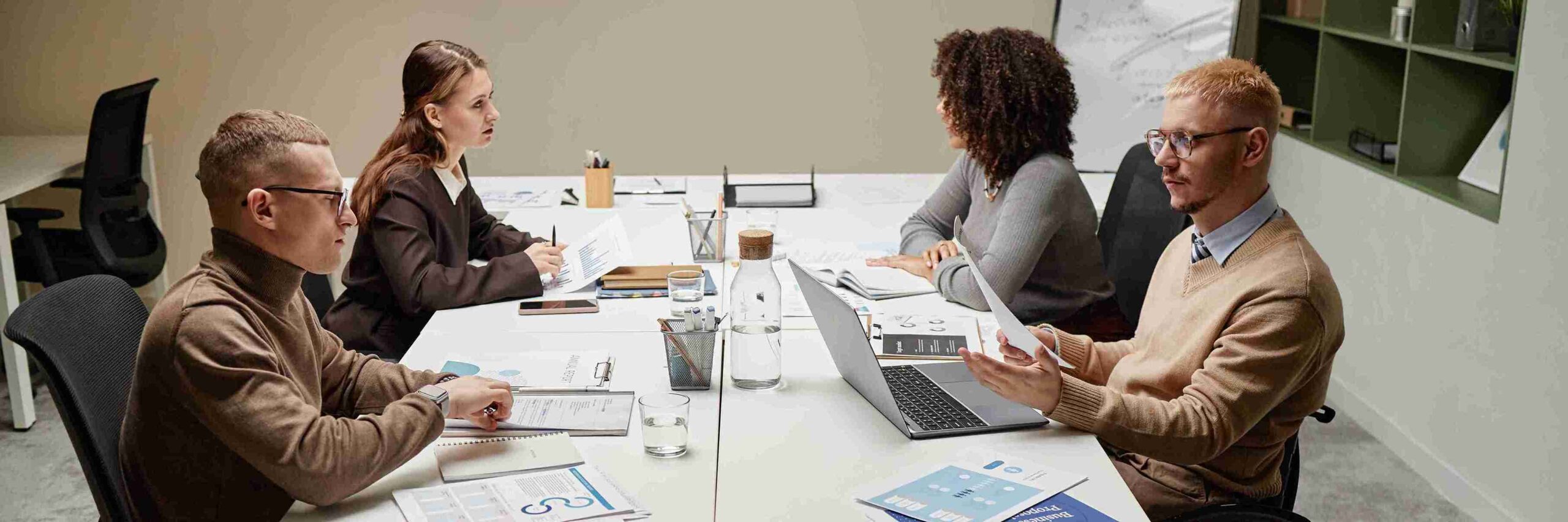 A group of people with laptops discussing strategies for establishing a UK branch office for overseas business expansion.