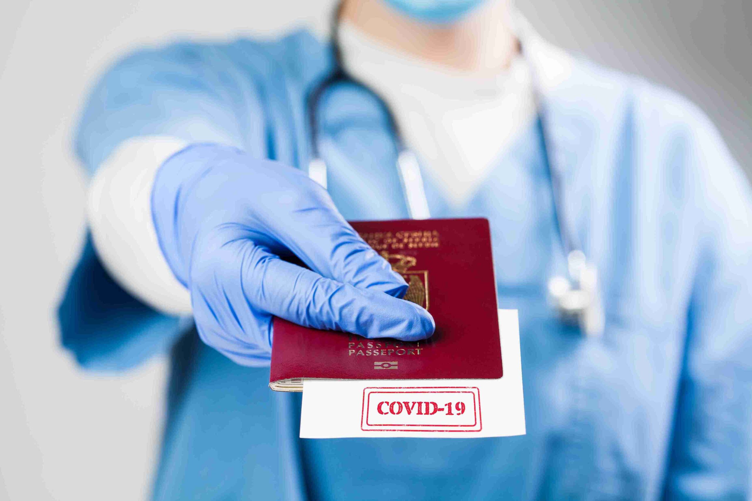 A doctor in blue scrubs holds a passport, symbolizing the Health & Care Worker Visa for international healthcare professionals.