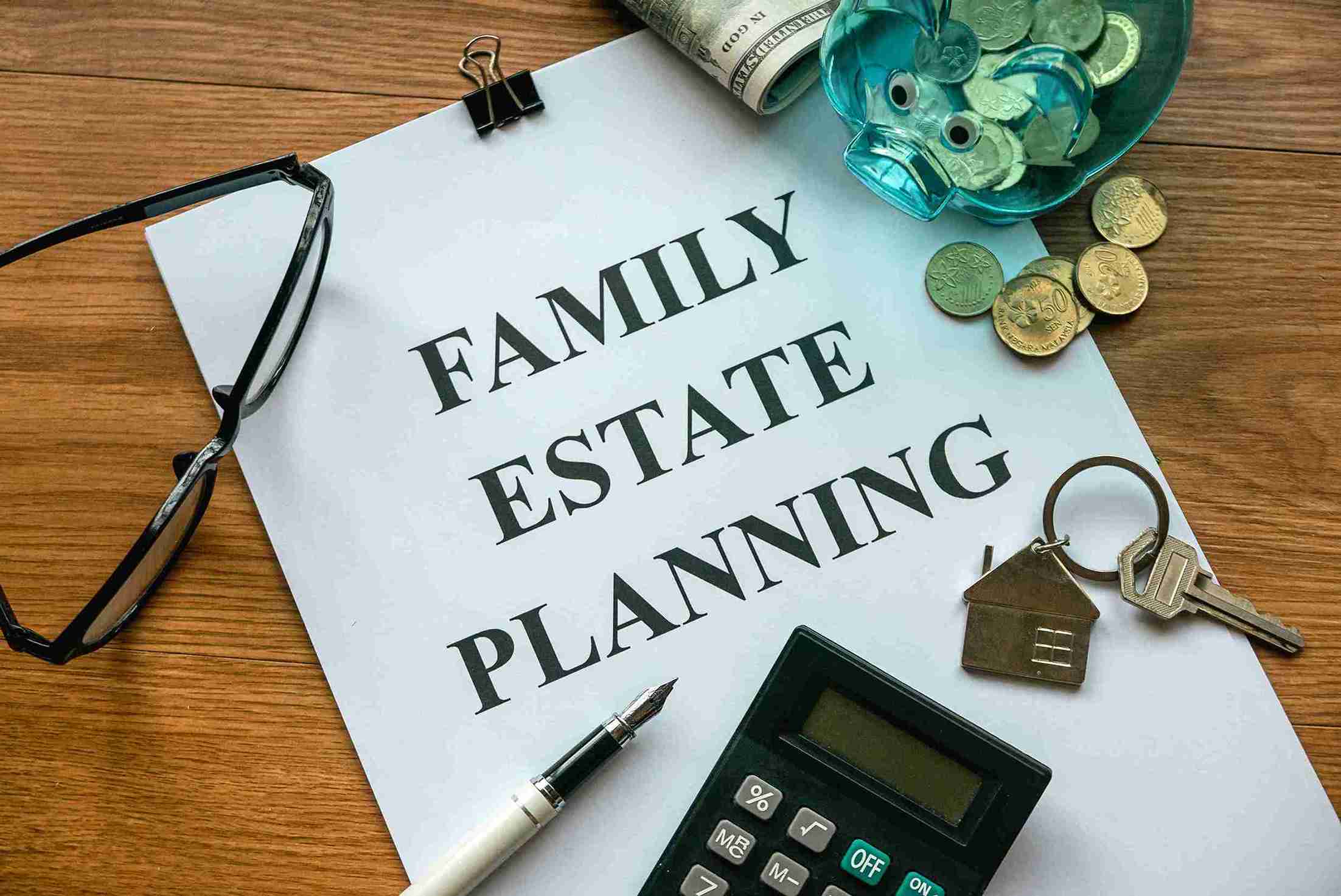 Document titled "Family Estate Planning" on a wooden desk with glasses, money, calculator, pen, and keys, conveying financial preparation.
