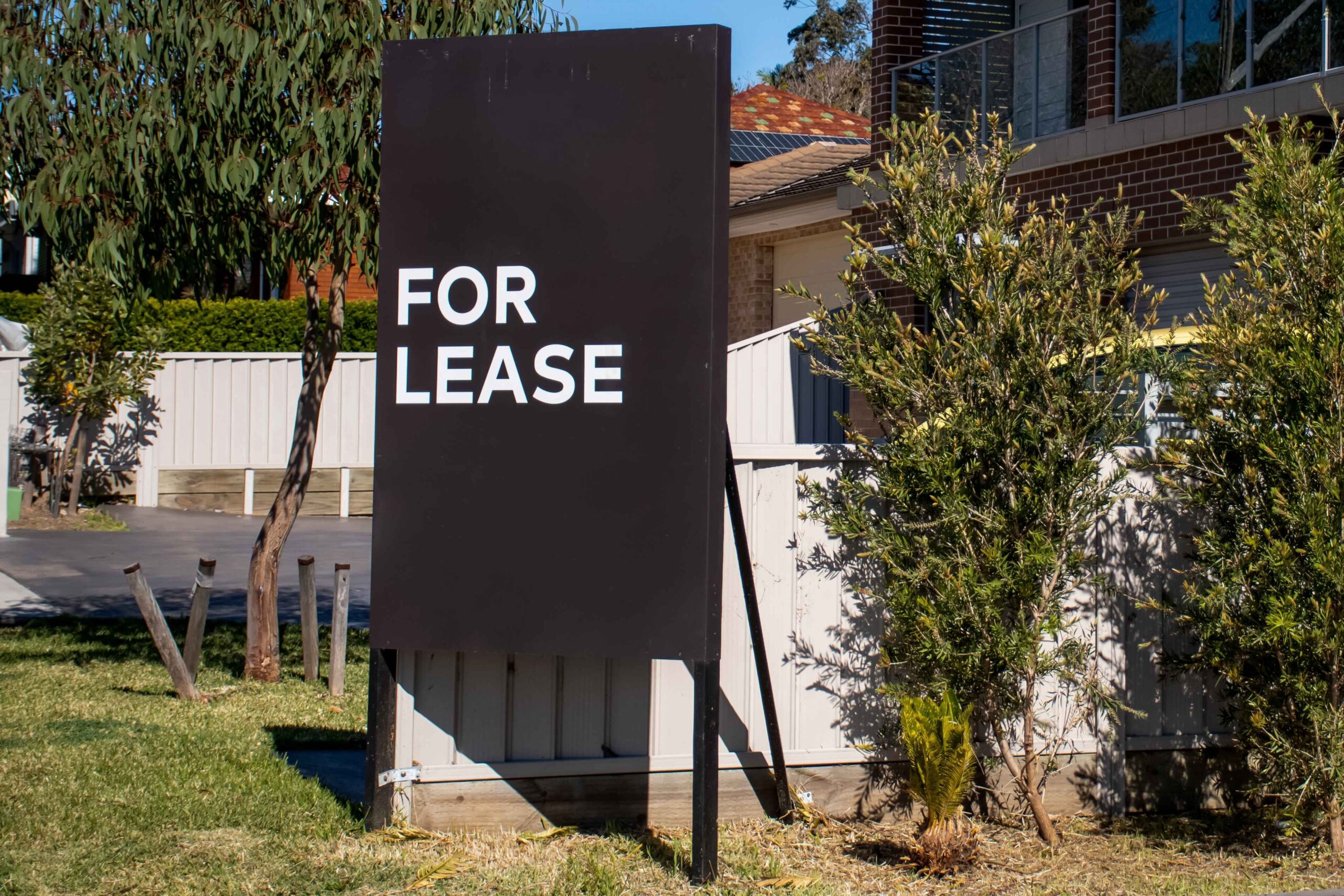 A for lease sign stands in front of a house, indicating availability for rental.