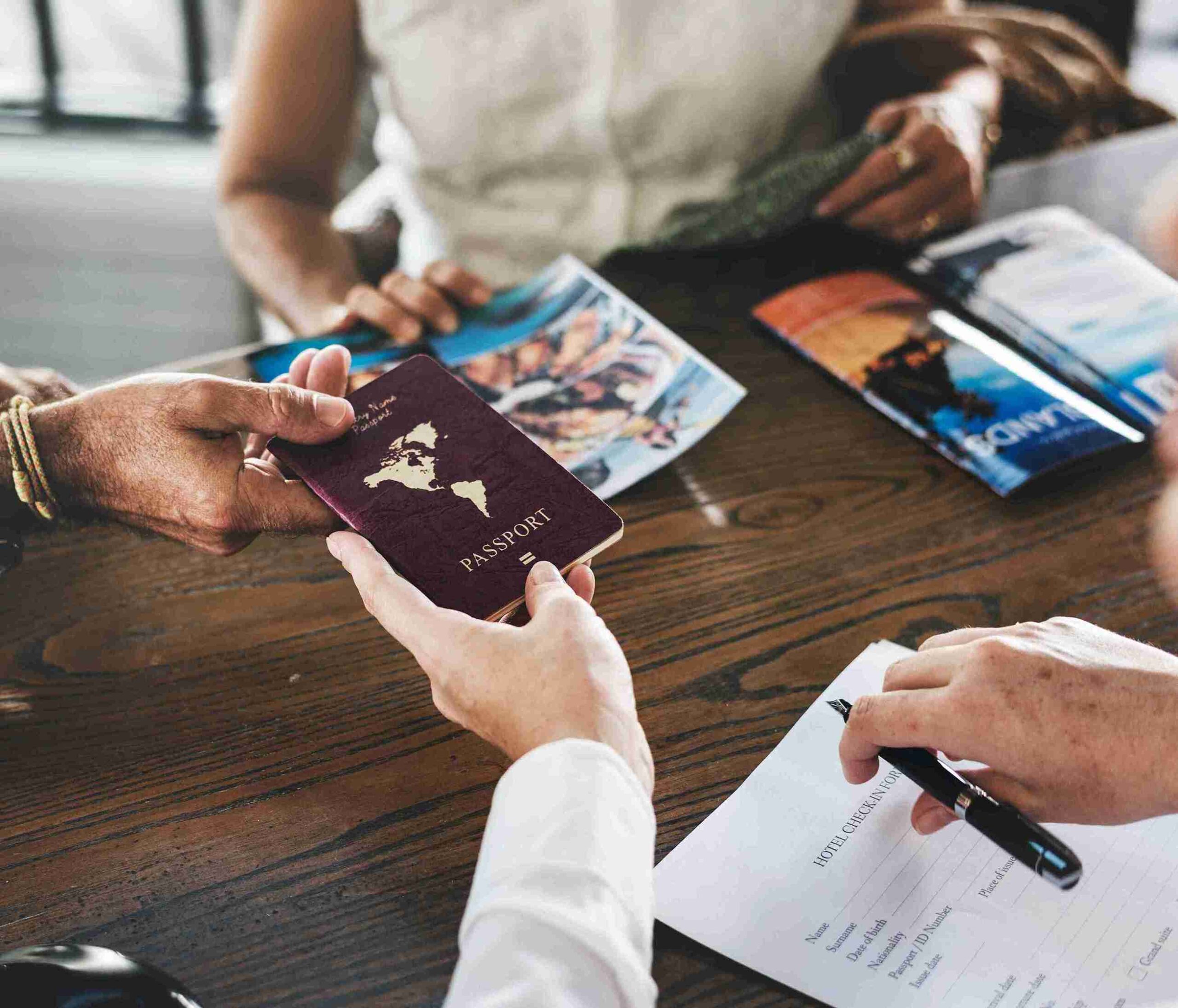 People gathered around a table, holding passports and documents, engaged in discussion or preparation for travel.