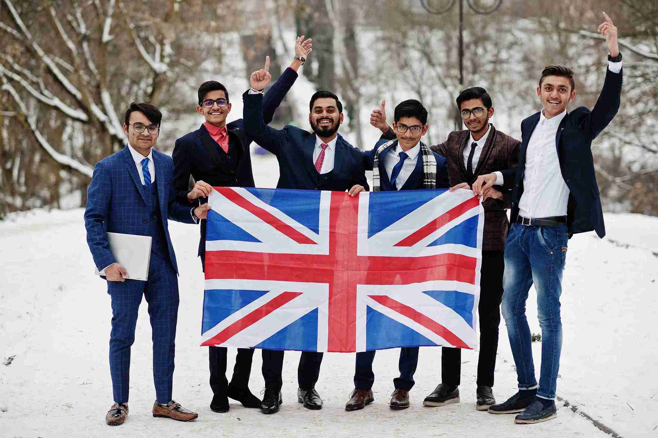 A group of men in suits proudly holding a British flag, representing the UK Global Talent Visa initiative.