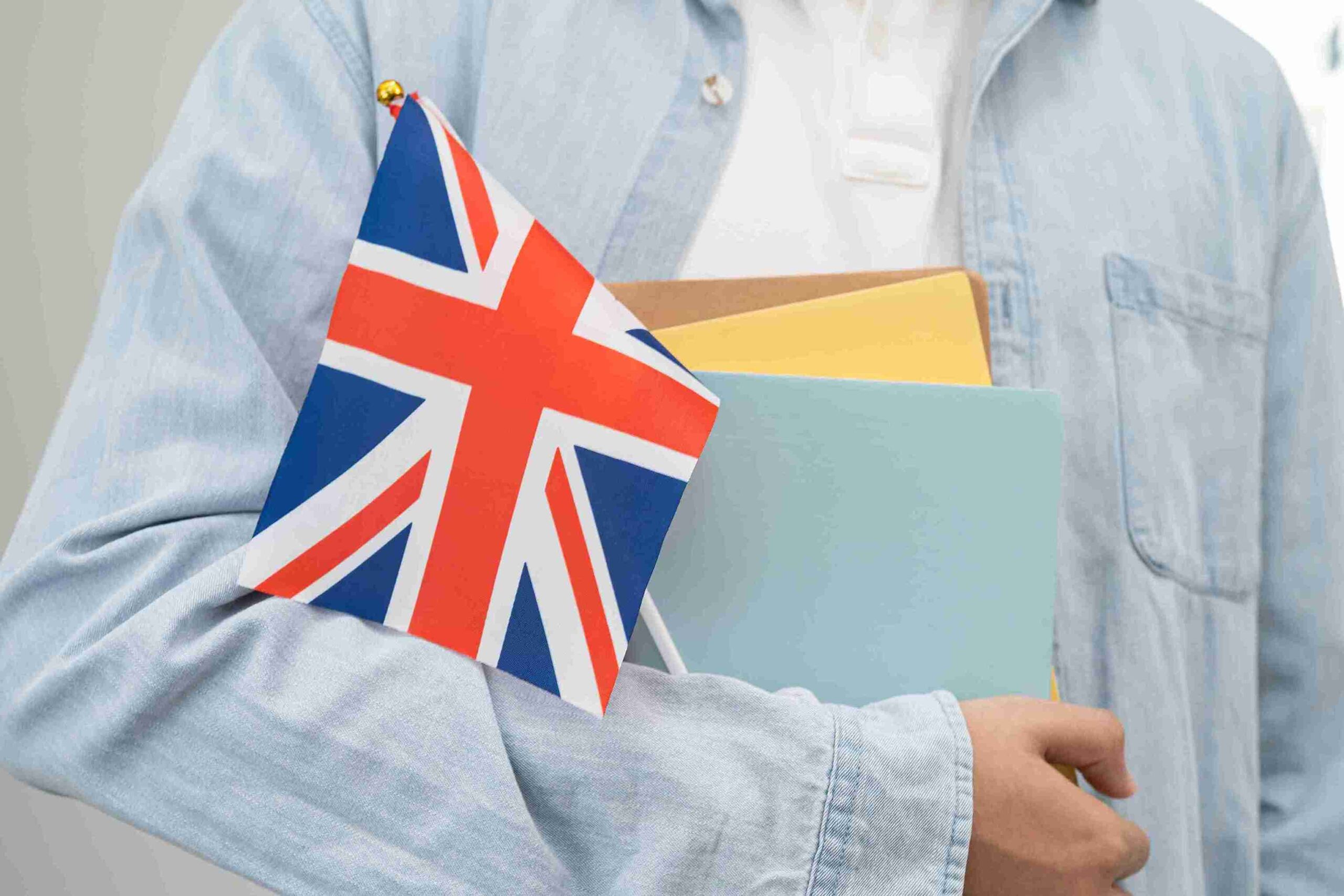 A man proudly holds a British flag in one hand and a folder in the other, smiling confidently.