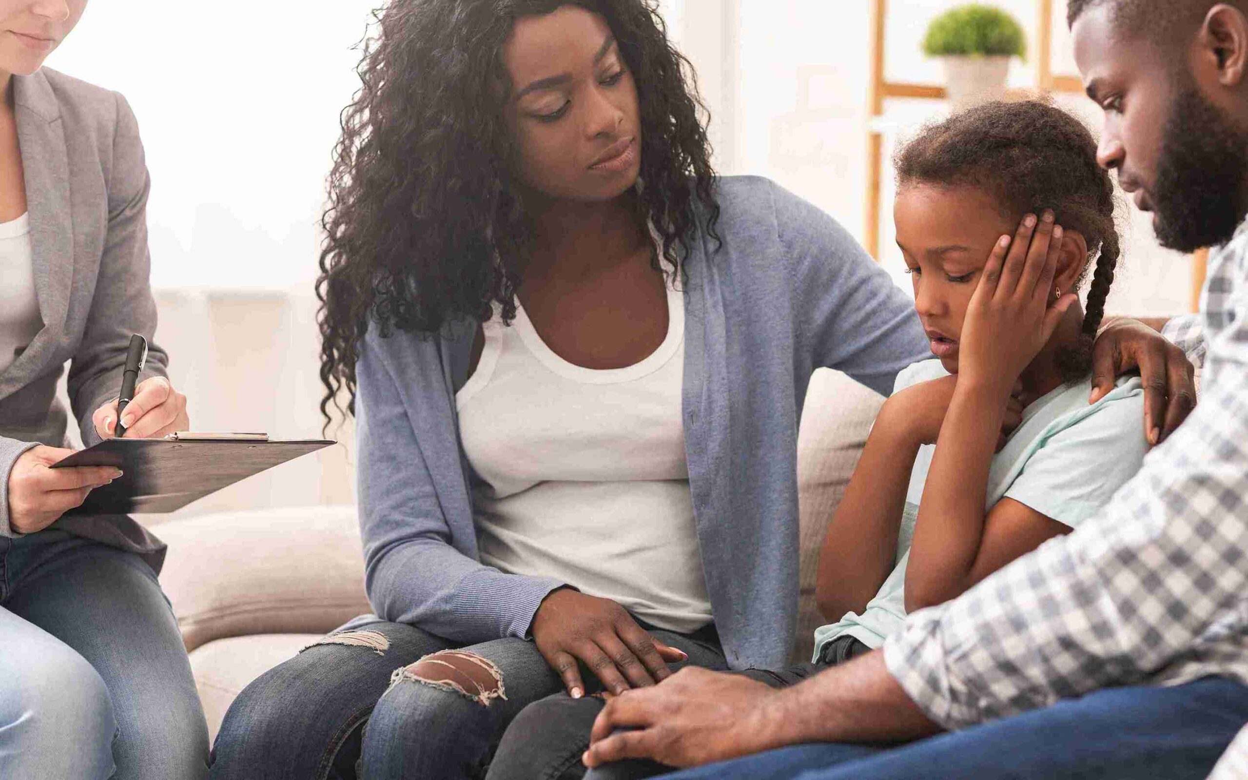 A family sits on a couch, discussing with a psychologist about child matters, focusing on the child's well-being.