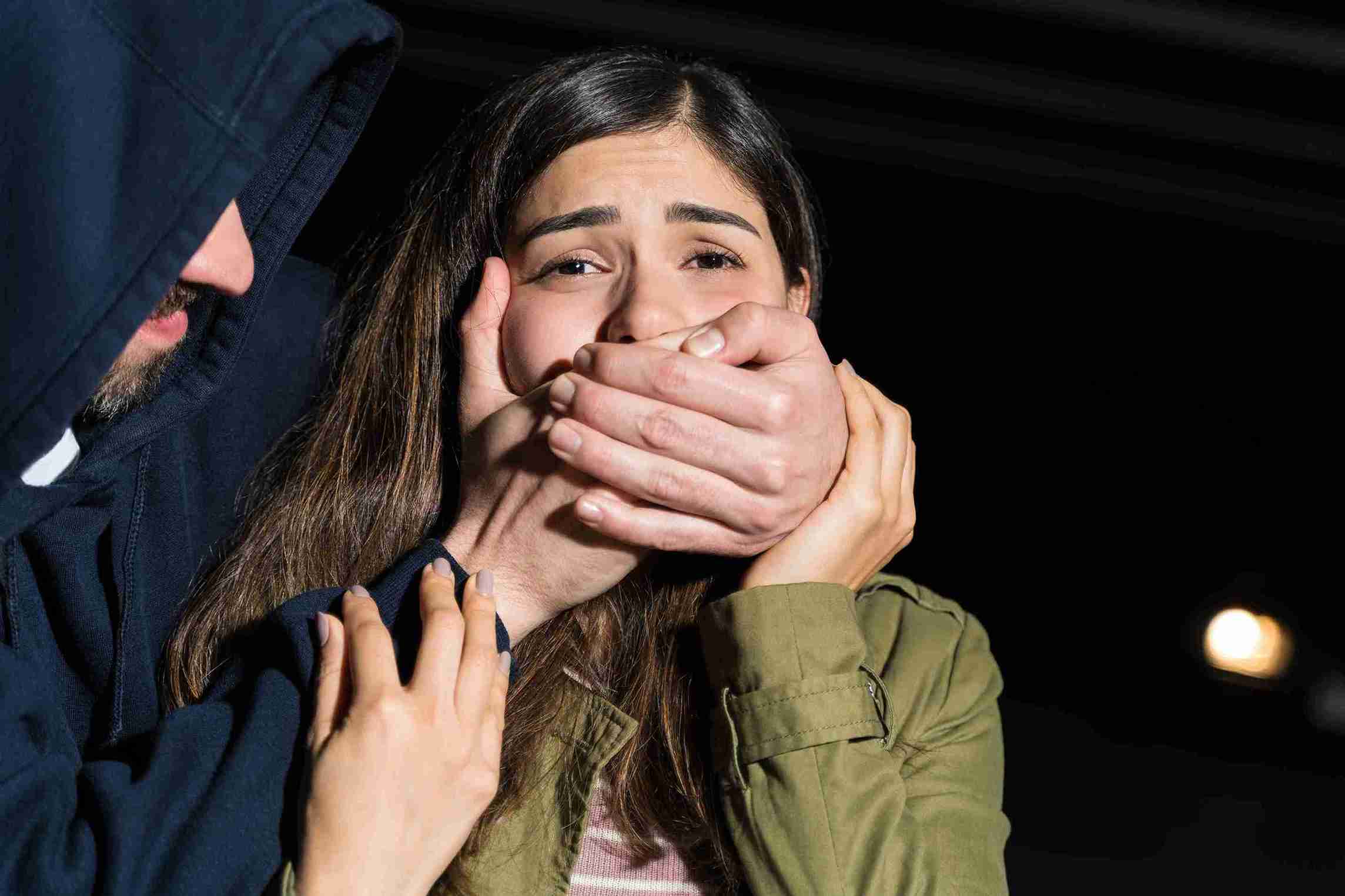 A man and woman hold hands, with the woman gently touching her face, symbolizing support among migrant victims.