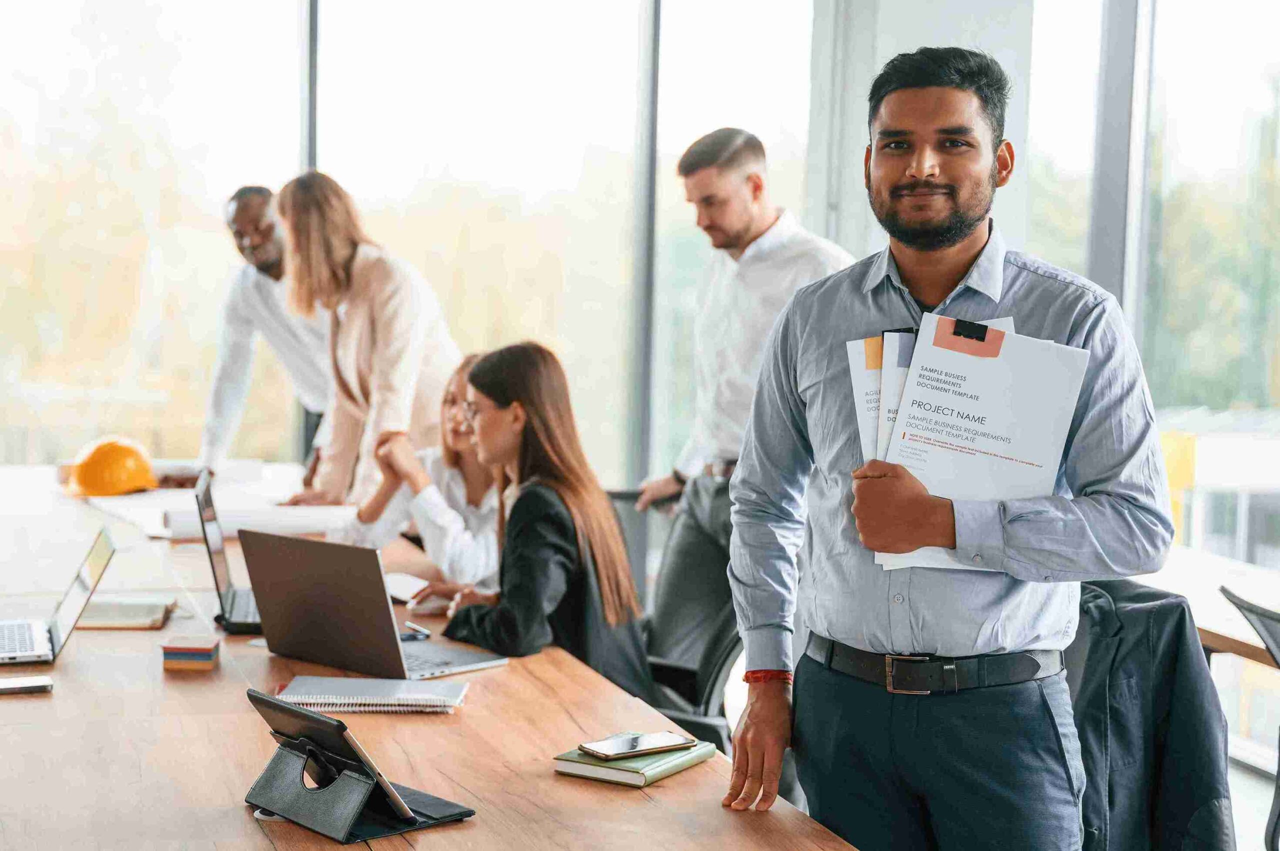 A man presents a document to a group of attentive people in a professional setting.