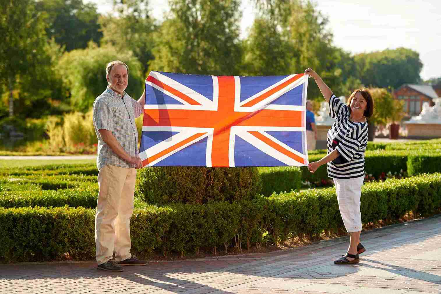 A man and woman proudly holding a British flag, smiling and standing together in a celebratory pose.