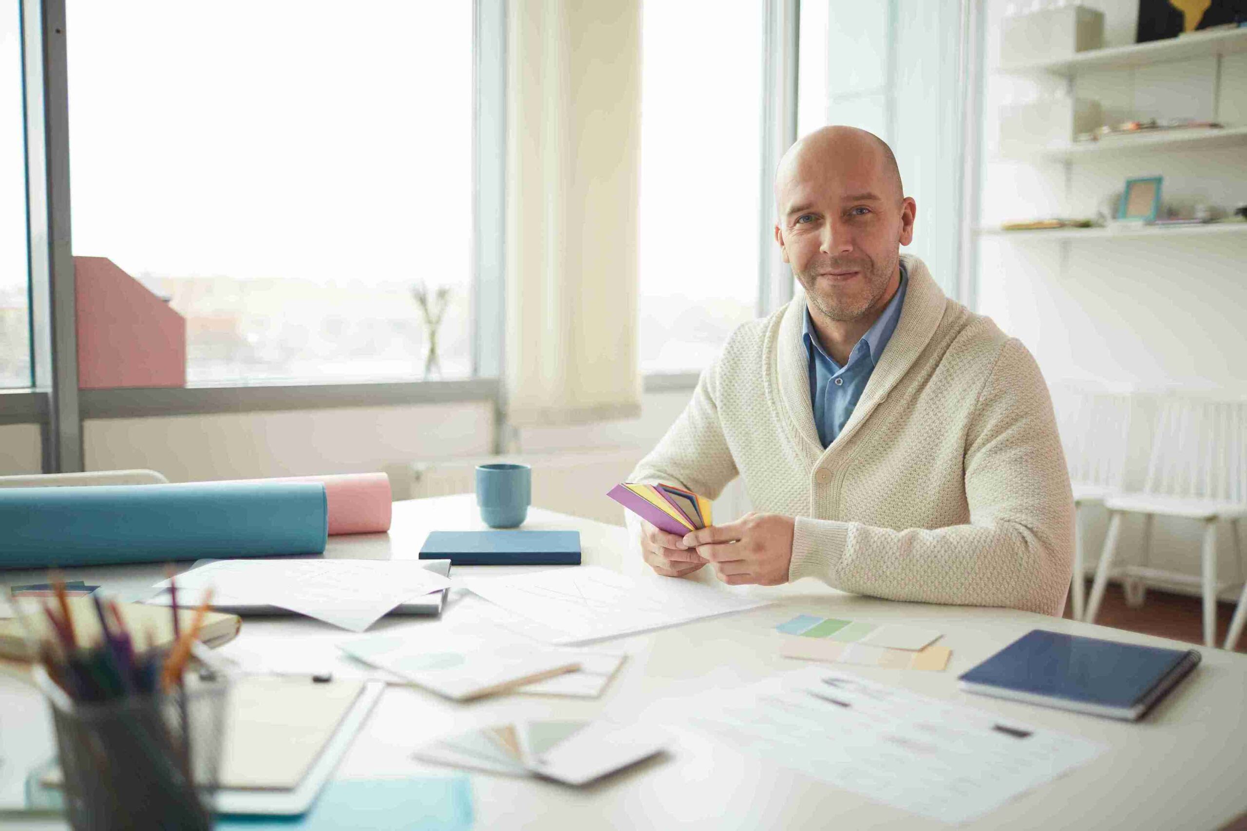 A bald man at a desk with a laptop and papers, focused on launching an innovative business.