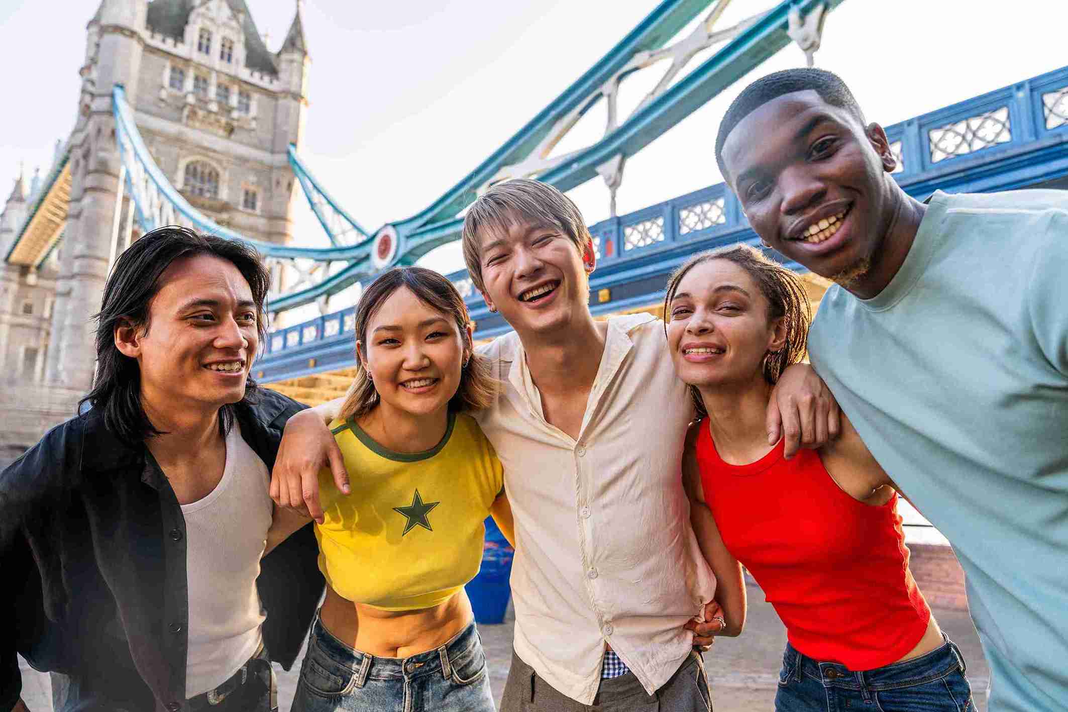 A group of young people smiling and posing in front of Tower Bridge, showcasing a fun moment in London.