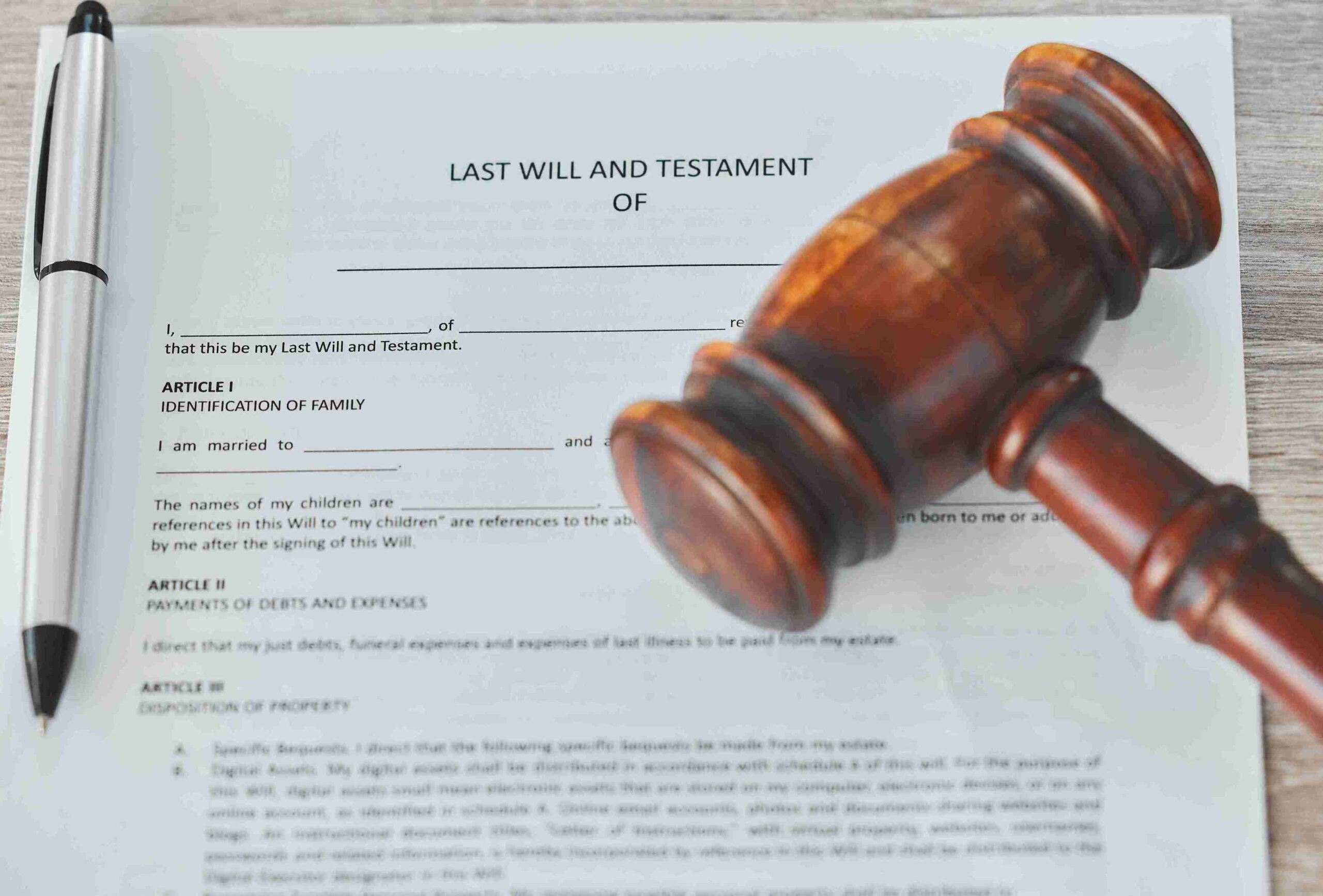 Close-up of a last will and testament document with a wooden gavel and a pen on top. The scene conveys a sense of legal formality and importance.