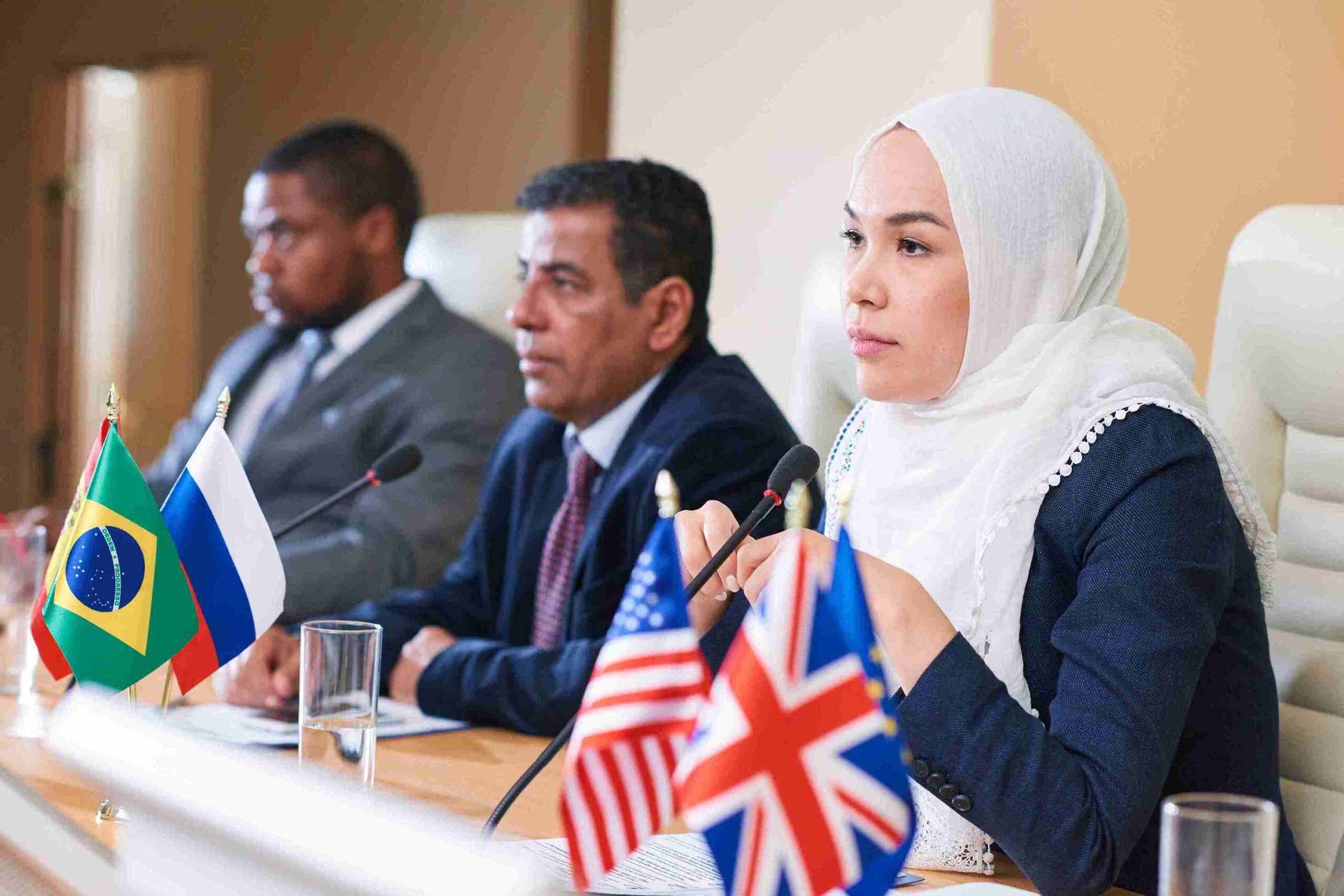A woman in a hijab sits at a table with flags, discussing immigration appeals and advocacy.