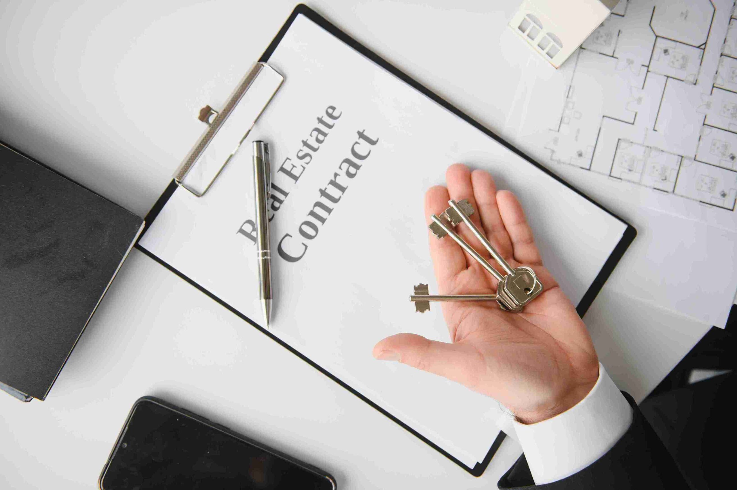 Two people shaking hands over a table with a house model, symbolizing a successful property transaction.