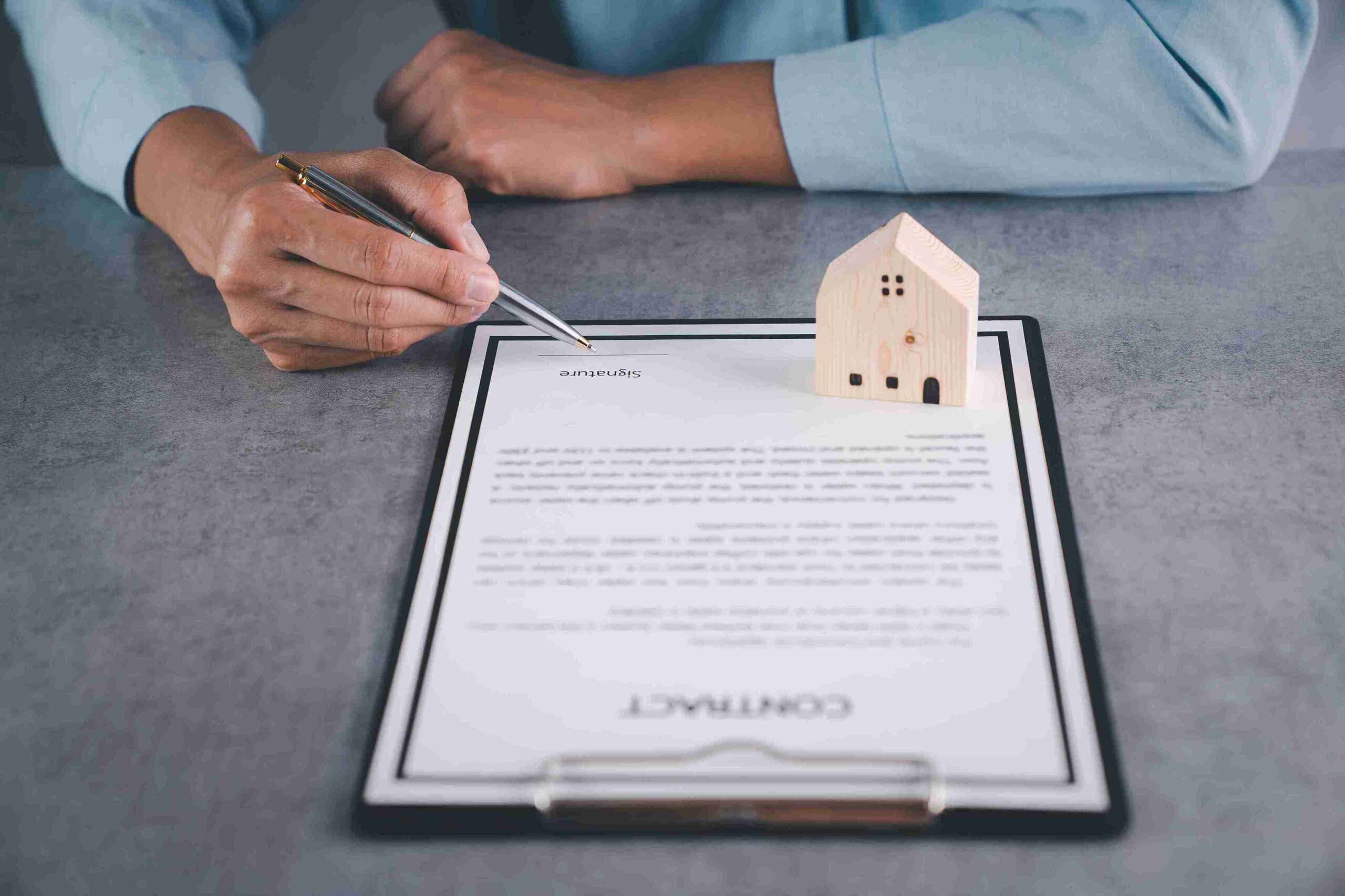 A man's hand holds keys and a pen on a clipboard, symbolizing property management and organization.