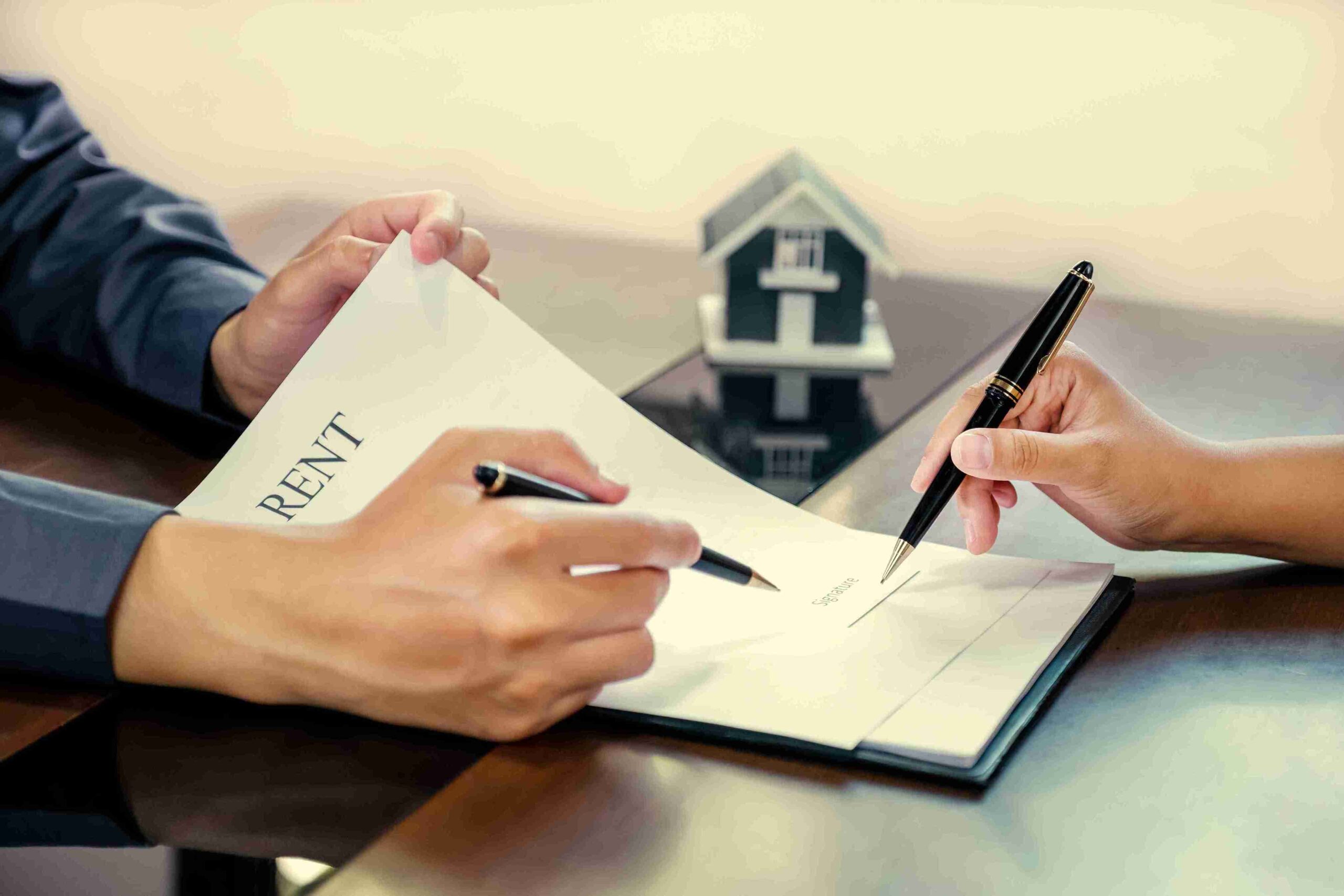 Two people signing an agreement at a desk, discussing terms and conditions of the rental contract.