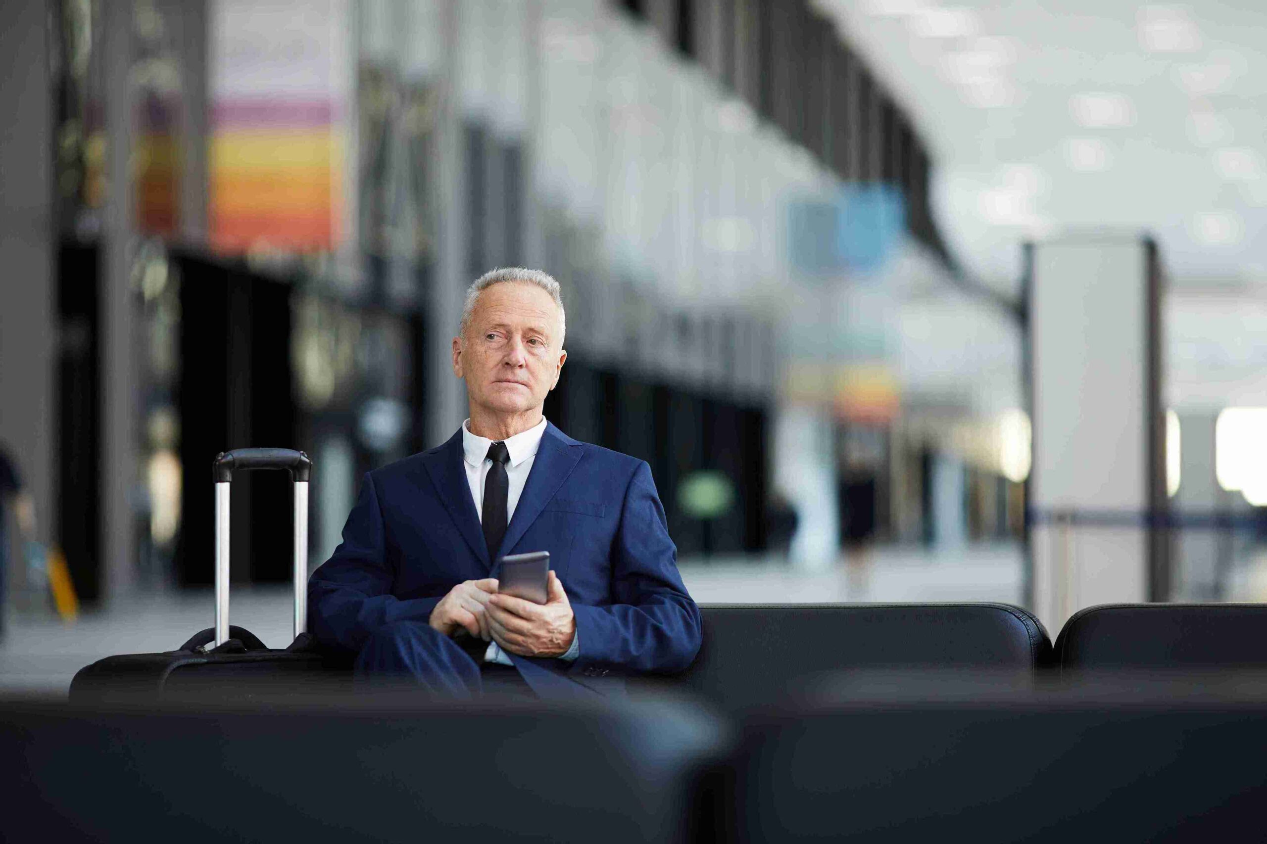 A man in a suit sits on a chair, focused on his phone, representing the Innovator Founder Visa for UK entrepreneurs.