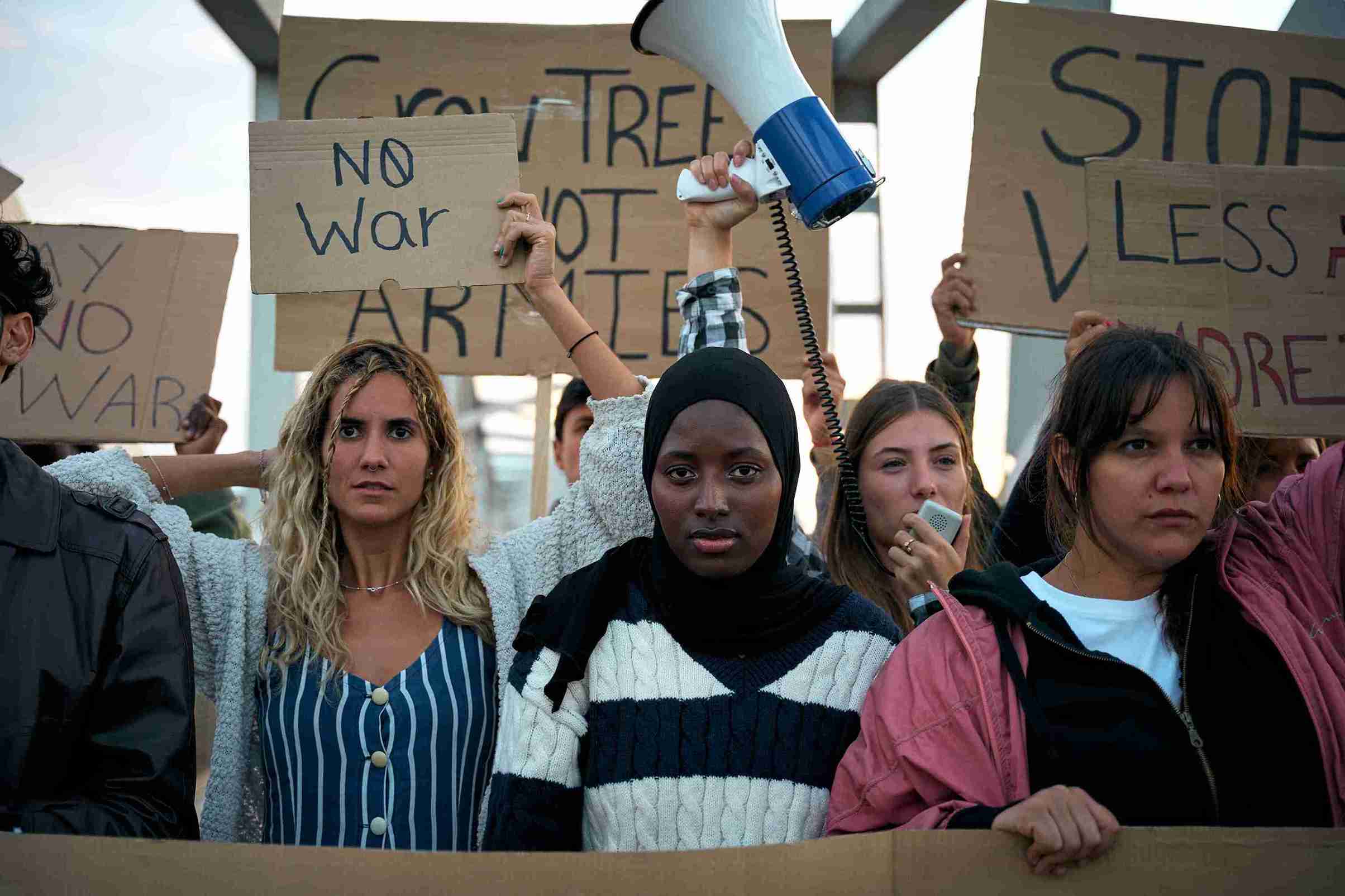 A diverse group of people standing together, holding colorful signs with various messages of support and activism.
