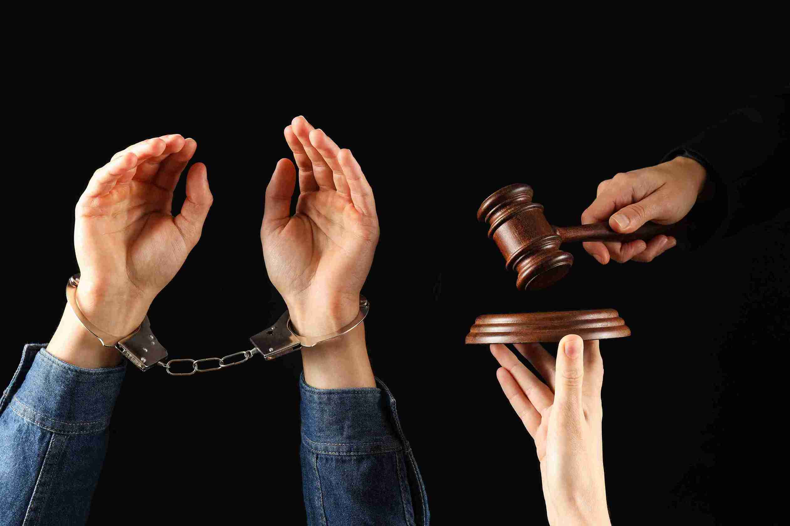 Hands holding a gavel alongside a hand with handcuffs, symbolizing justice and law enforcement.