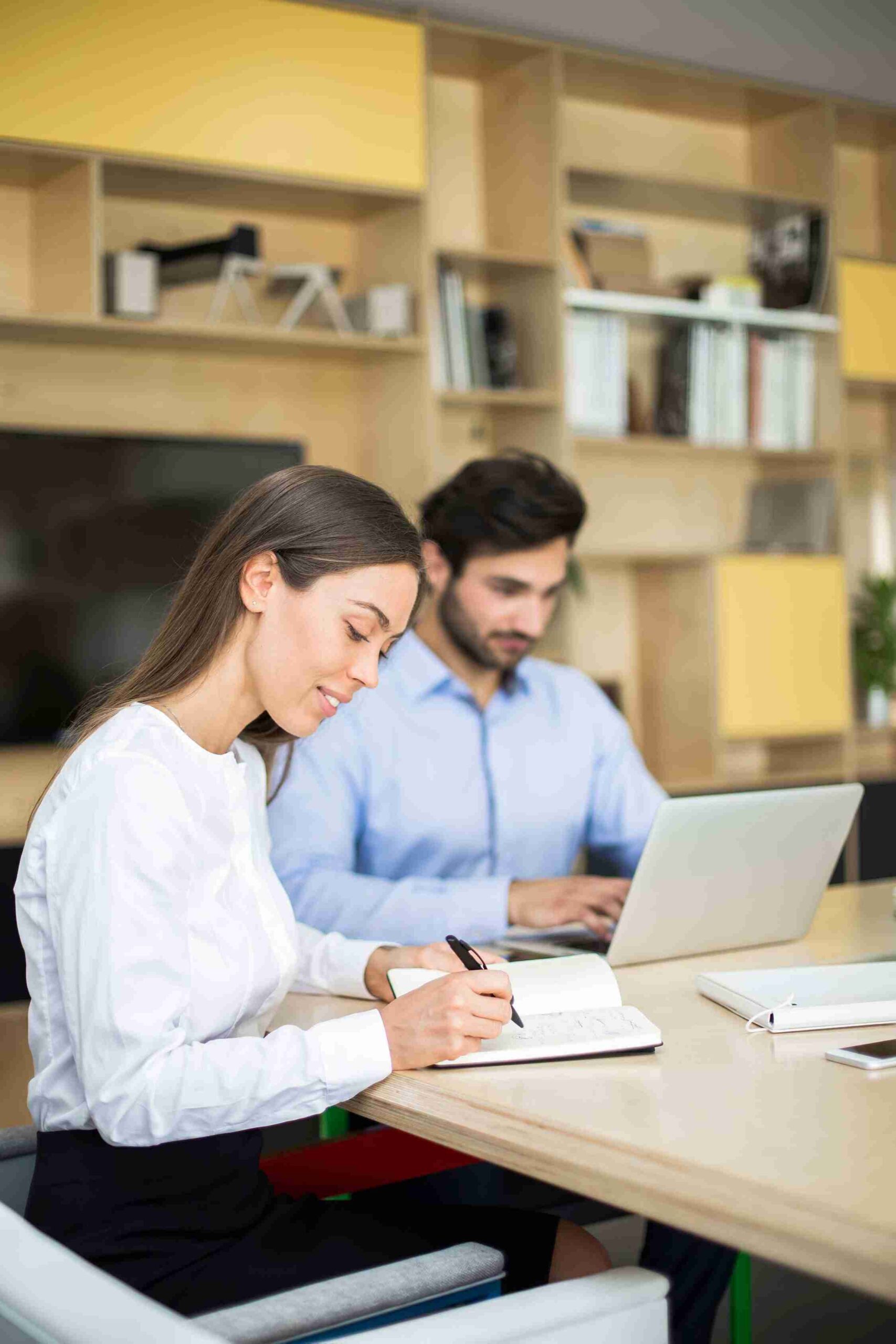 A man and woman discuss UK Business set-up while sitting at a table with a laptop open between them.