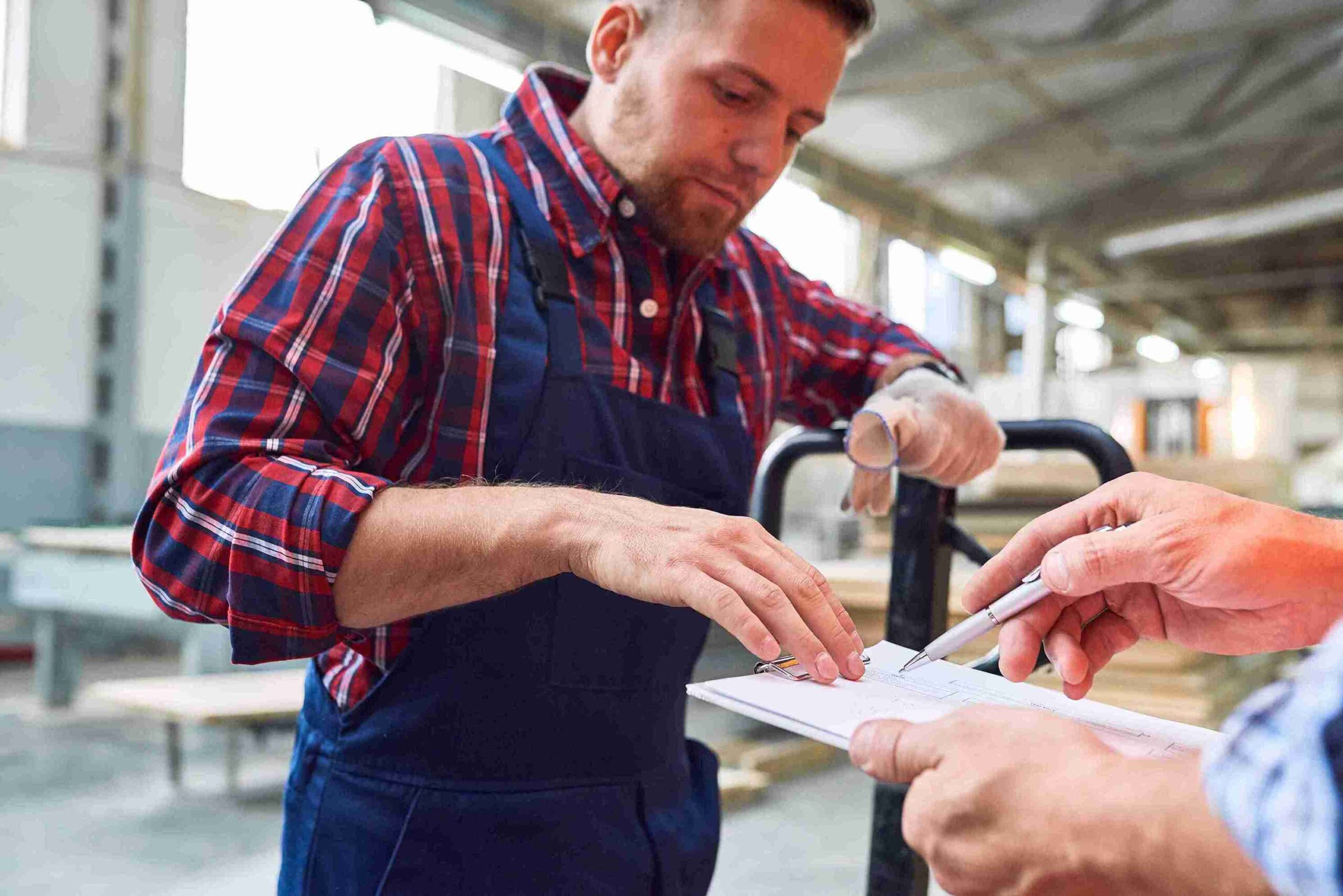 A man in overalls and a woman in an apron collaborate on paperwork for a Self-Sponsorship Skilled Worker Visa.