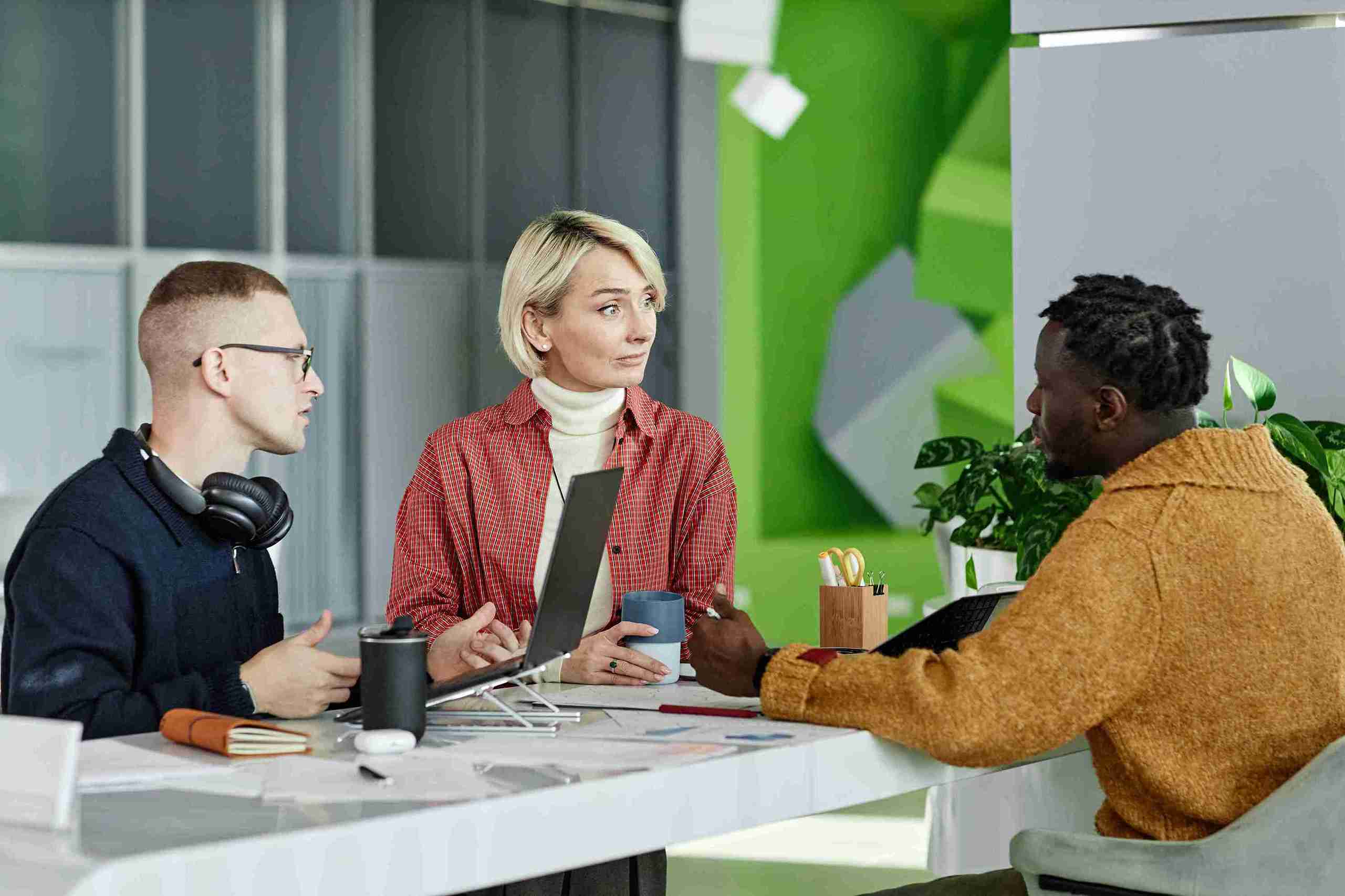 Three experienced entrepreneurs discussing innovative, viable, and scalable new business ideas at a table in the UK.