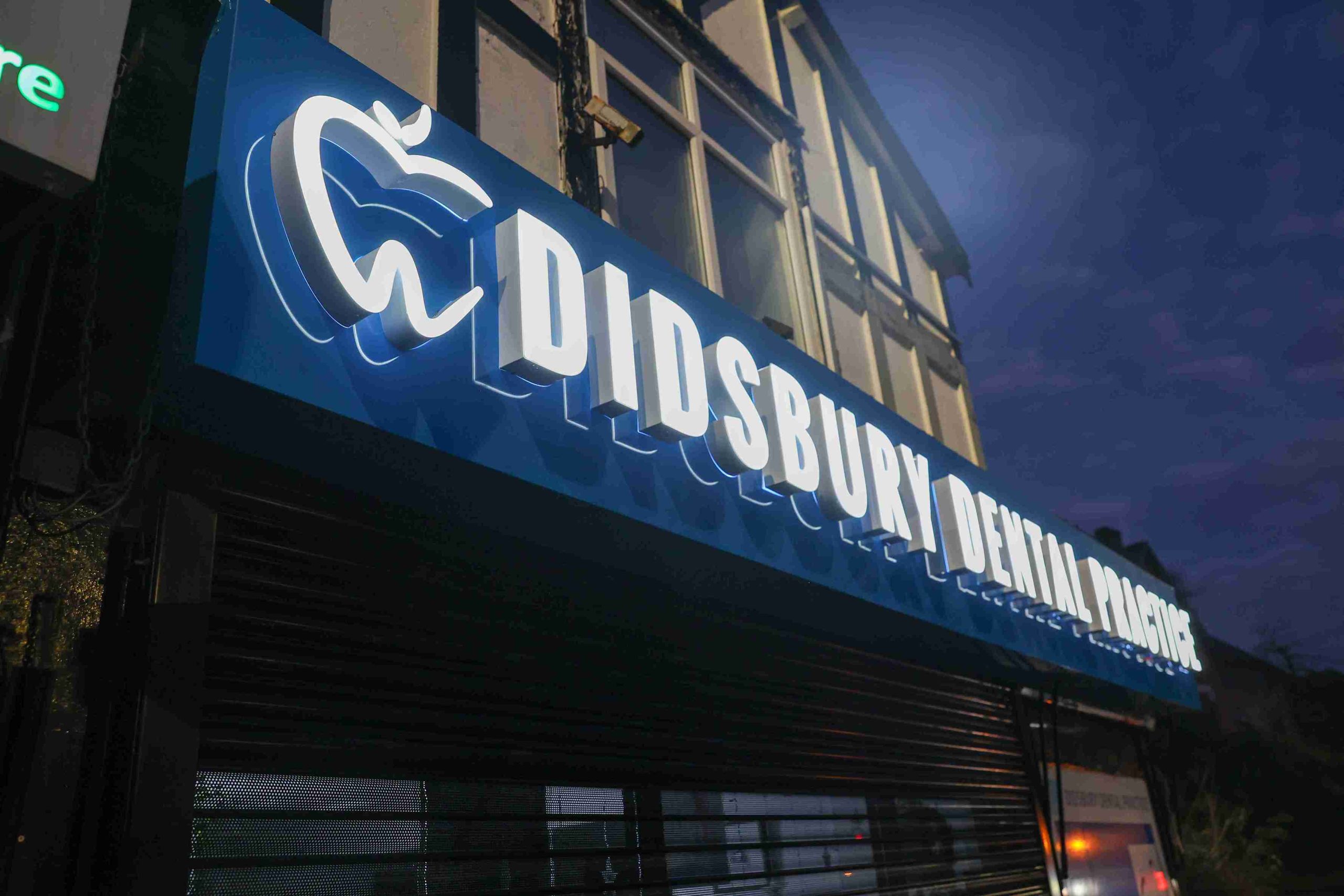 Blue neon sign reading "Disso Dental Clinic" glowing against a dark background.