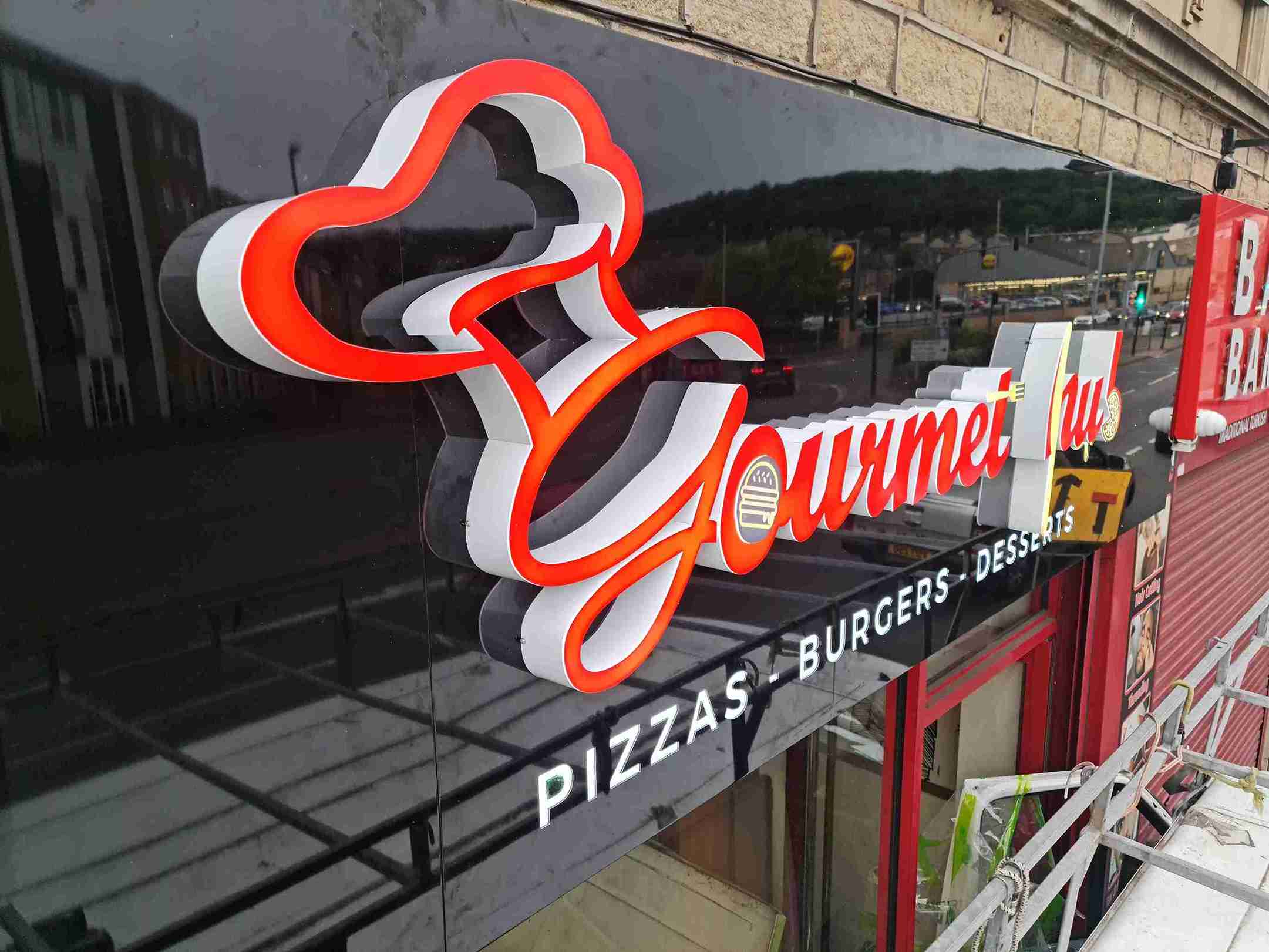 A colorful restaurant sign mounted on the side of a building, inviting customers to dine inside.