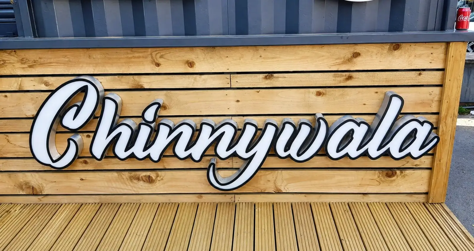 A rustic wooden sign displaying the word "Chinywala" in bold letters, set against a natural background.